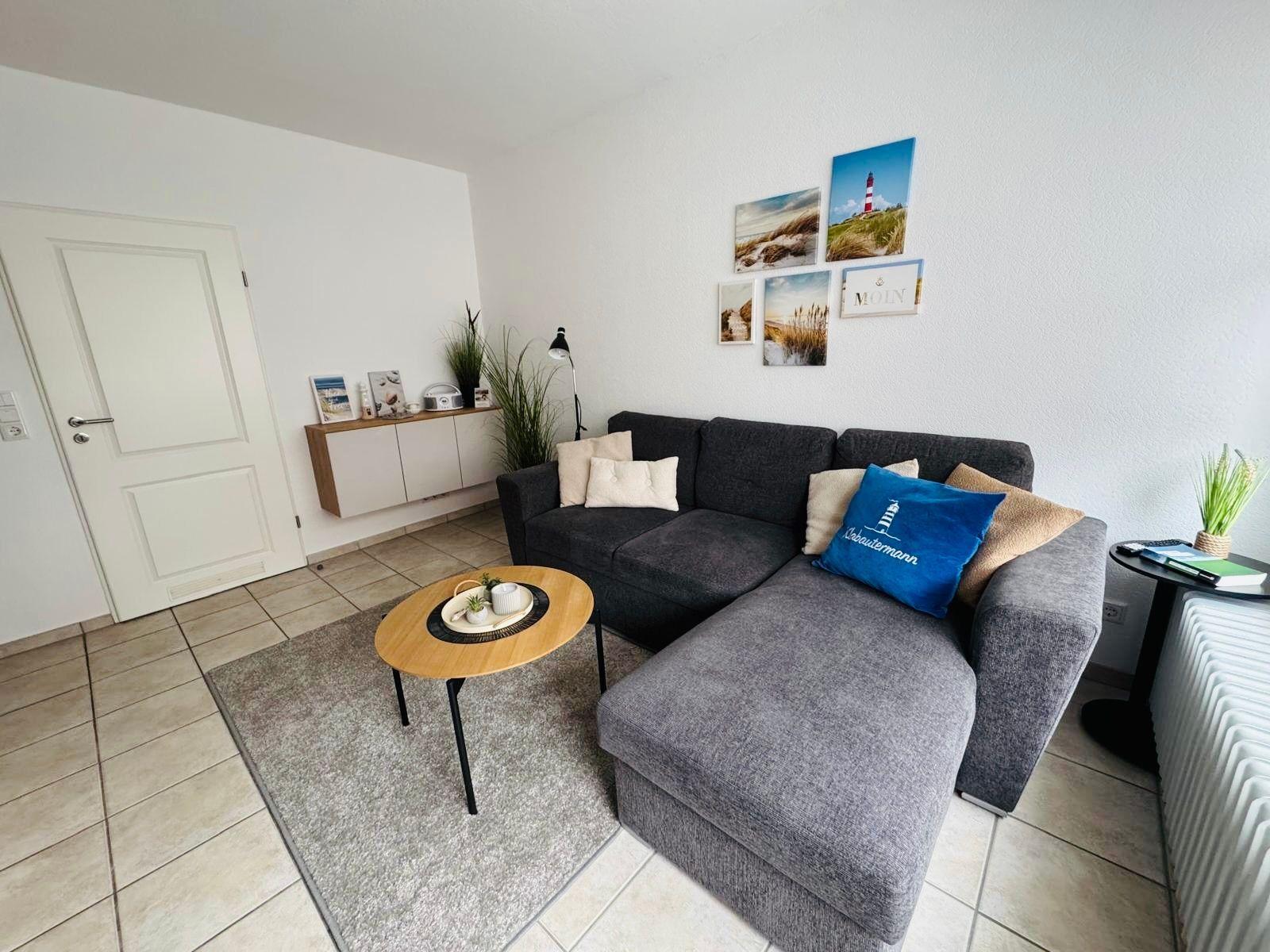 Living room with gray sofa, round table, and wall pictures.
