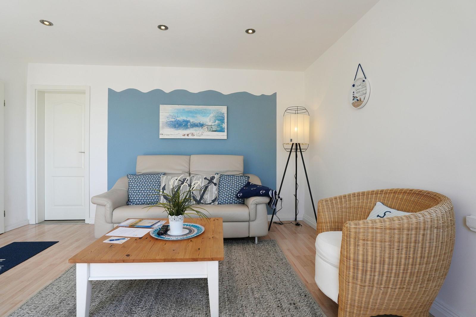 Wohnzimmer mit Sofa, Kissen, Couchtisch und Stuhl. Wand mit blauer Wellenmalerei.