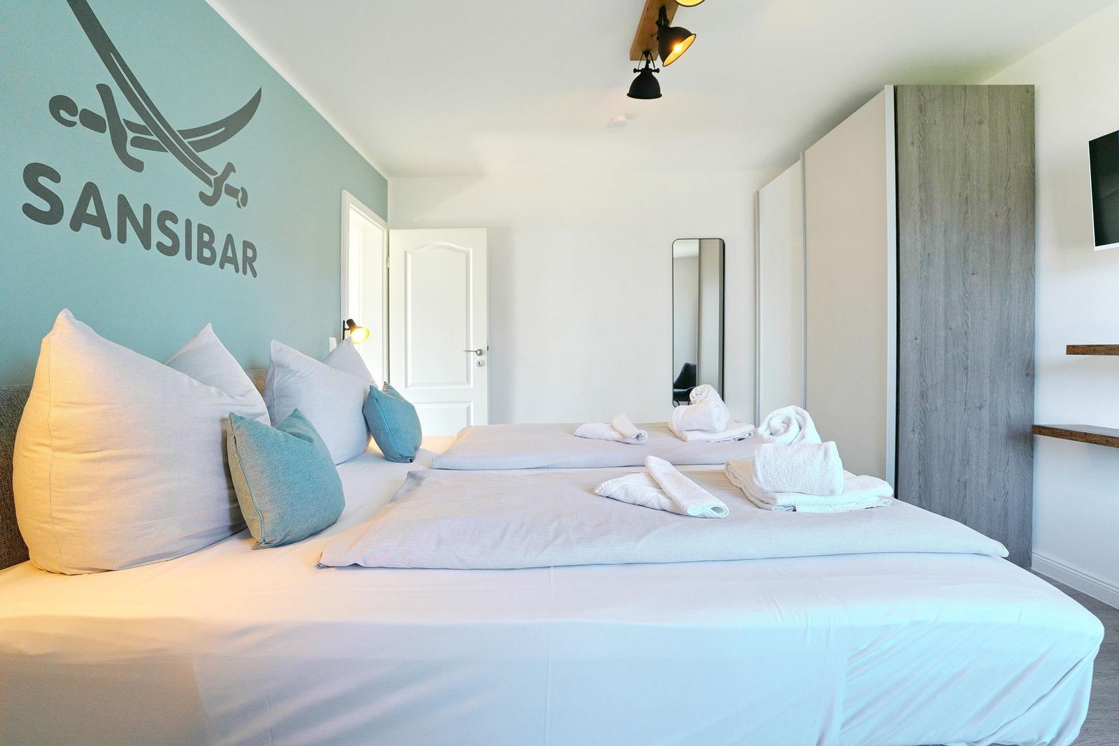 Schlafzimmer mit Doppelbett, Wanddekoration und Badetuch.
