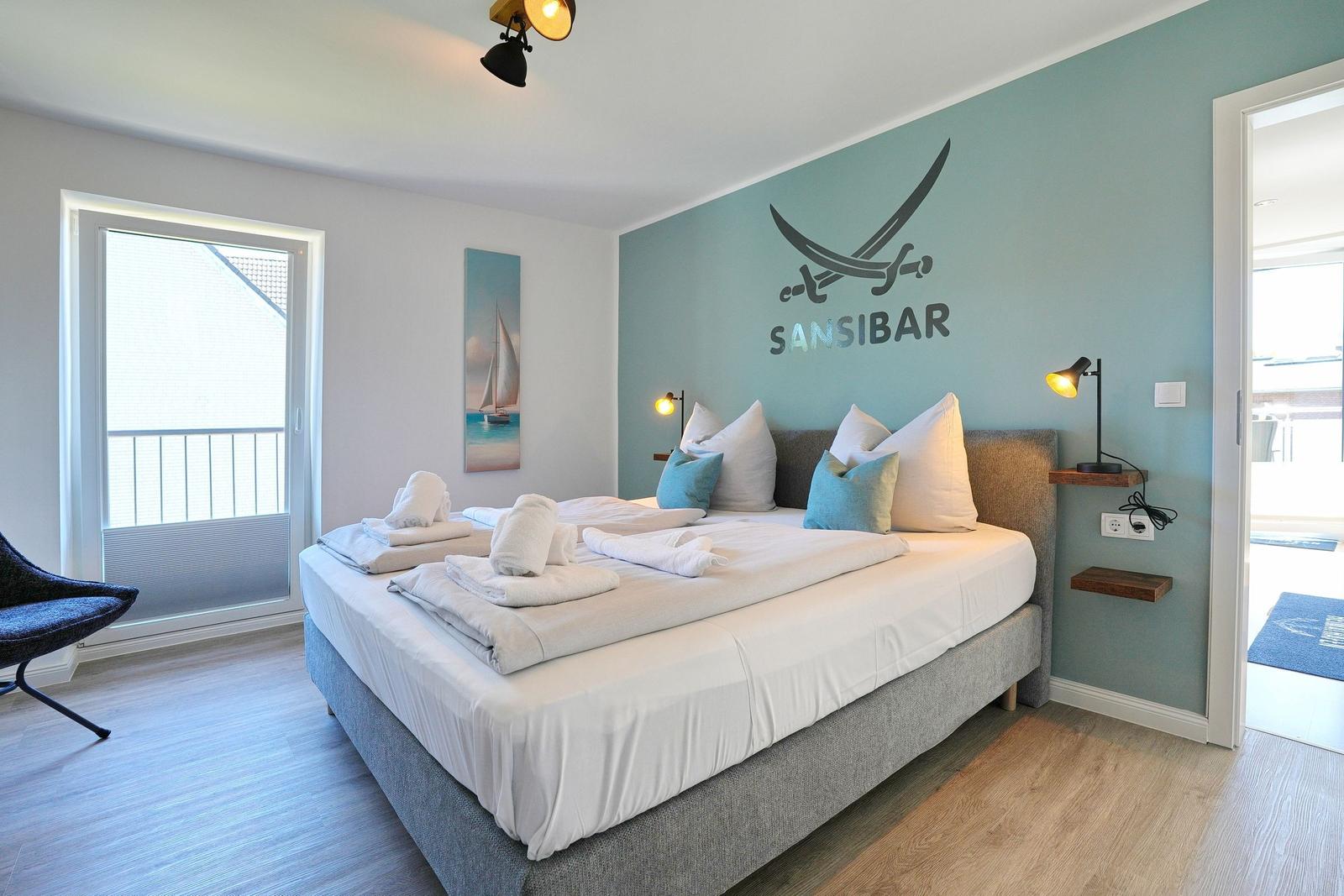 Schlafzimmer mit Bett, Wanddekoration und Balkontür.