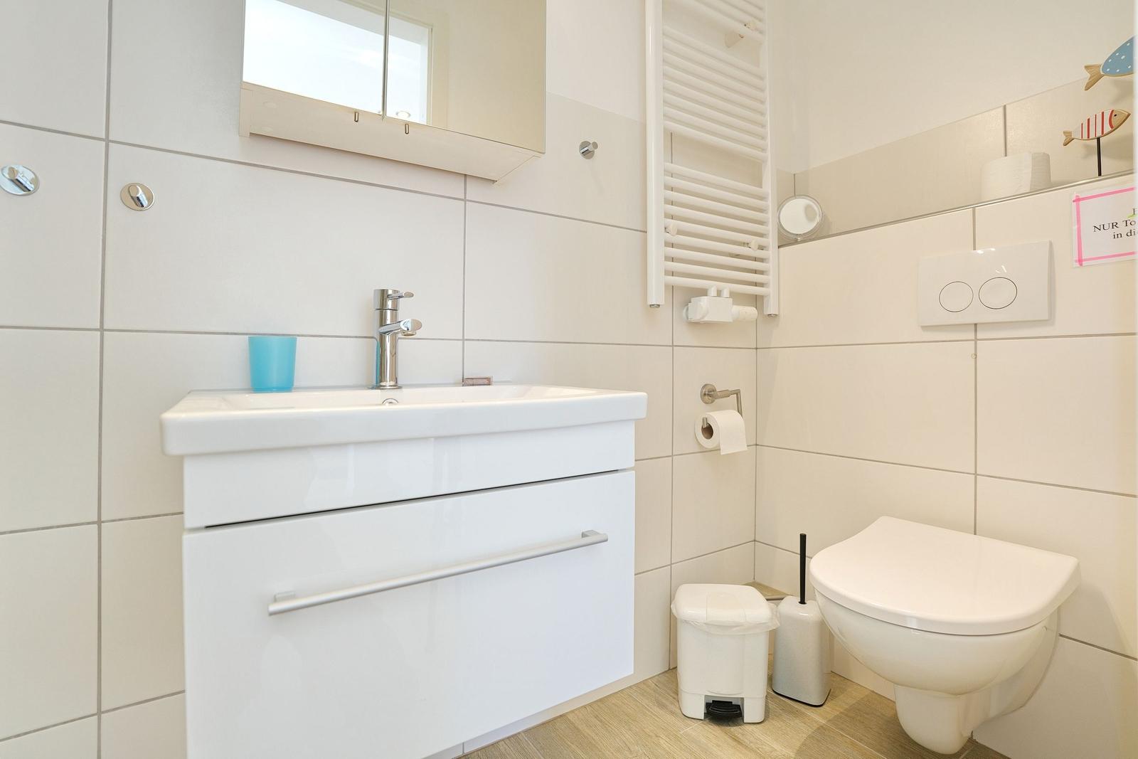 Badezimmer mit Waschbecken, Toilette und Heizkörper an der Wand.