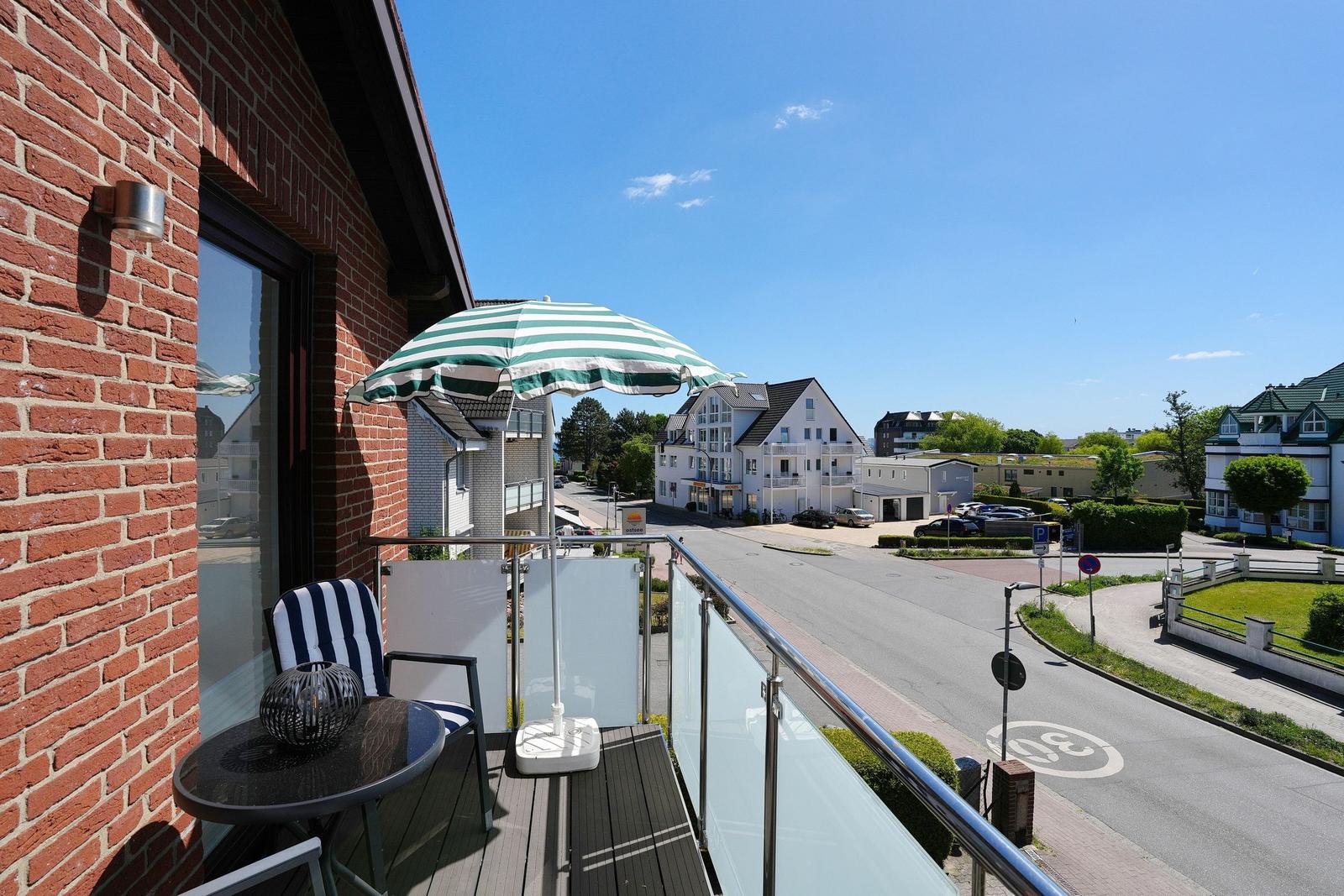 Terrasse mit Sonnenschirm und Tisch. Blick auf Straße und Gebäude.