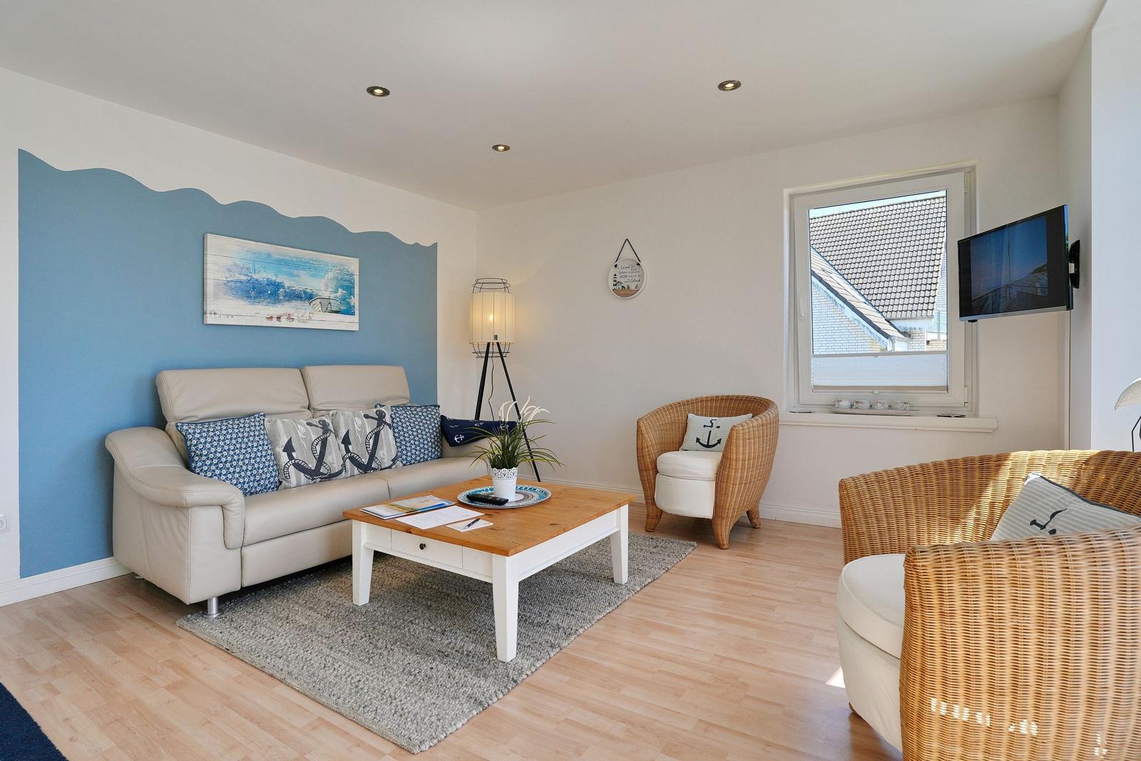 Wohnzimmer mit Sofa, Kissen und Esstisch. Wand mit blauer Wellenmalerei.