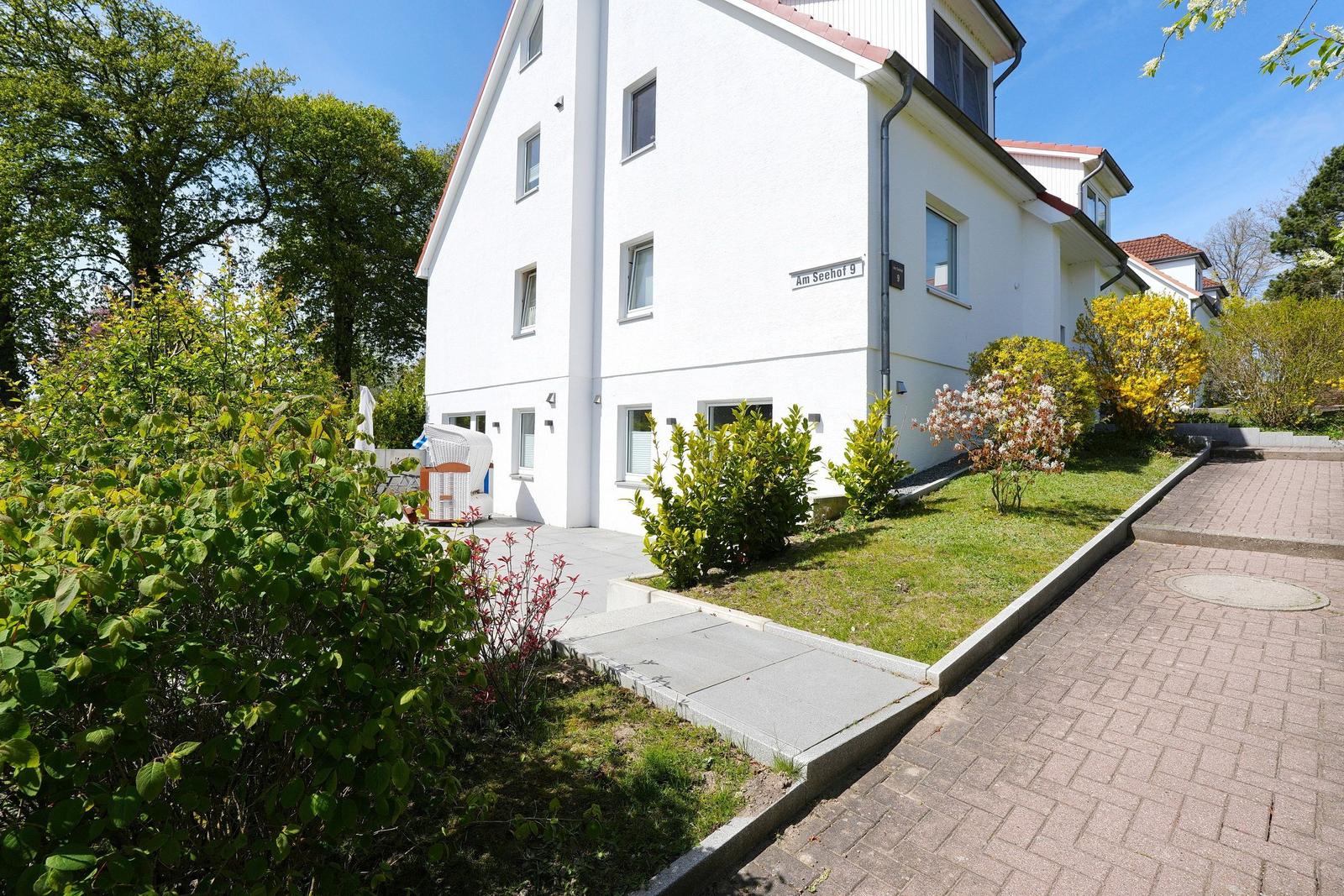 Weiße Ferienwohnung mit Garten und gepflastertem Weg. Adresse: Am Seehof 9.