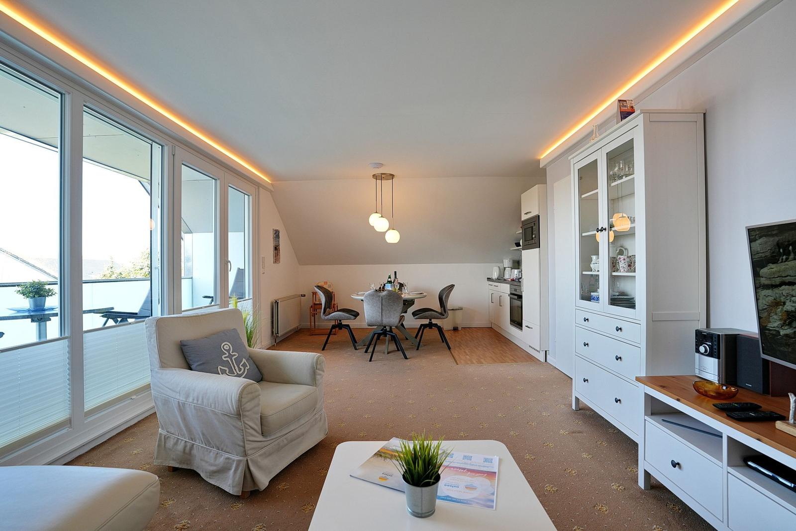 Wohn- und Essbereich mit Balkon, Küchenzeile und Wohnzimmermöbeln.
