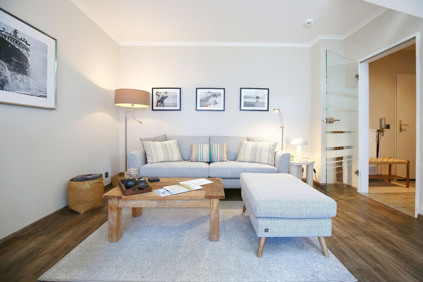 Wohnzimmer mit Sofa, Tisch und Beistelltisch. An der Wand hängen Bilder.