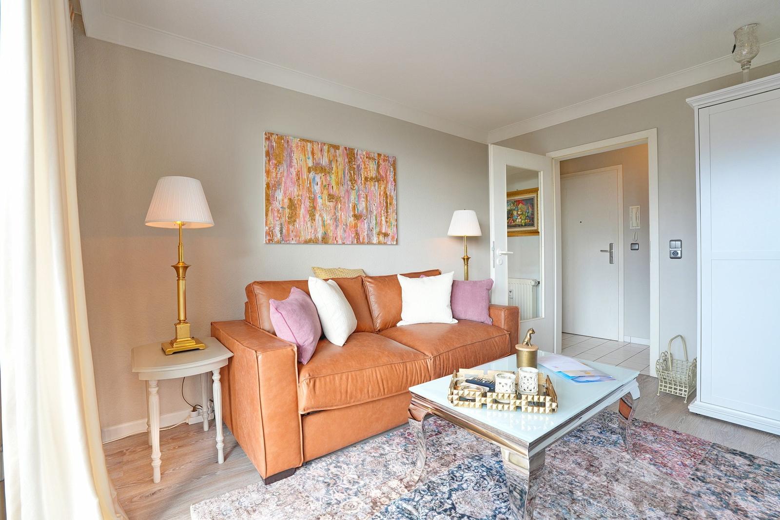 Wohnzimmer mit braunem Sofa, Couchtisch und Wandbild.