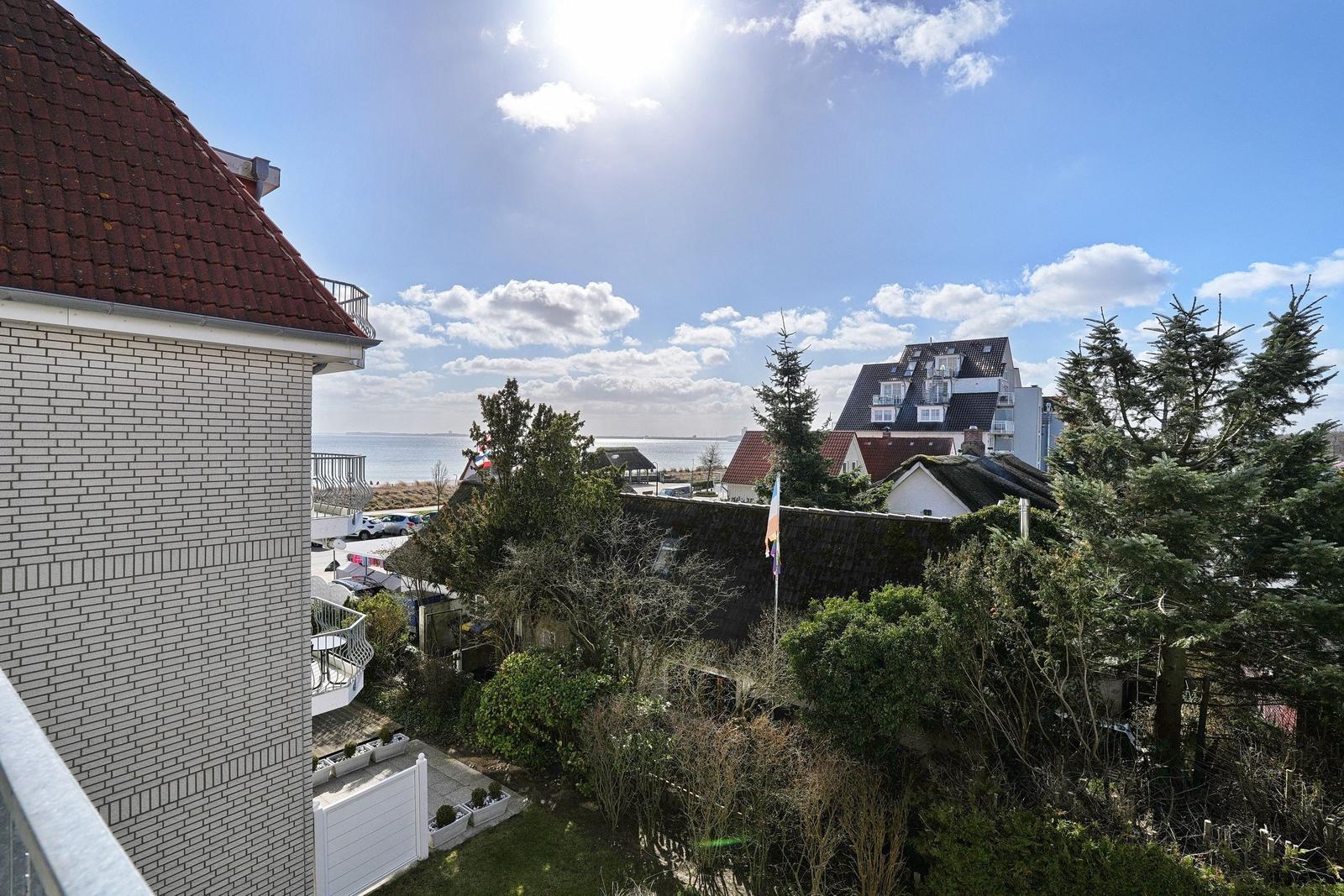 Blick auf den Strand und das Meer unter blauem Himmel mit weißen Wolken.