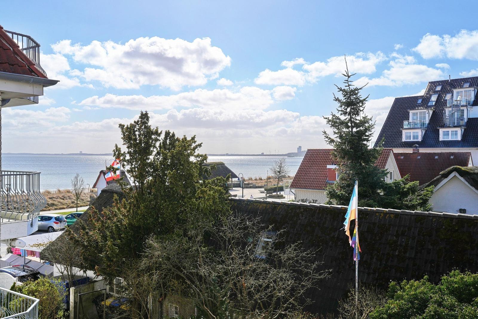 Panoramablick auf See und Dächer unter blauem Himmel mit weißen Wolken.