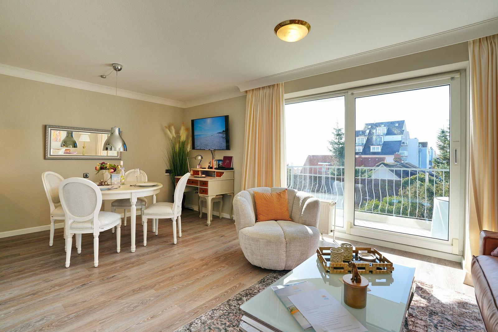 Wohnzimmer mit Essbereich, Balkon und TV. Holzboden und große Fenster.
