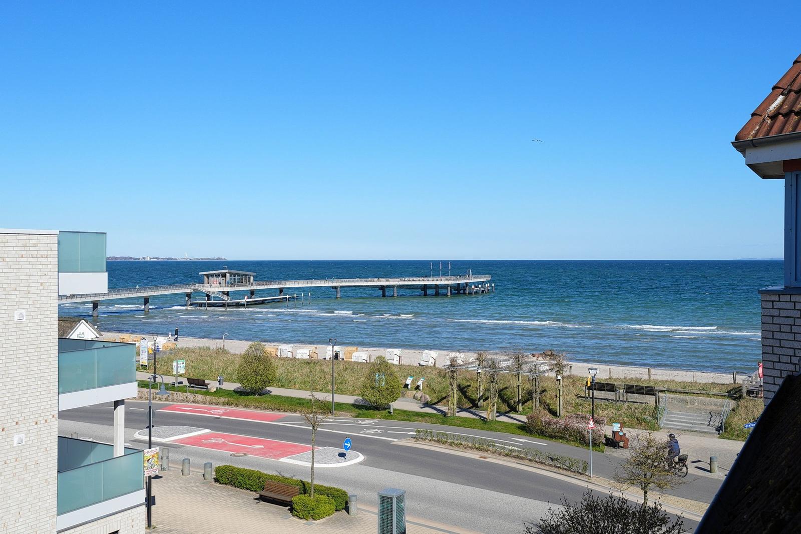 Meerfront mit Steg, Strand und Fahrradweg. Blick von einem Gebäude aus.