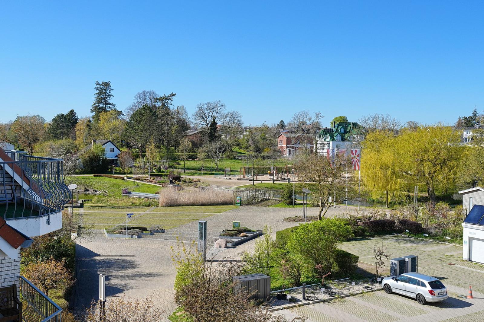 Haus mit Blick auf grünen Park und Spielplatz mit Fahrrad und Auto.