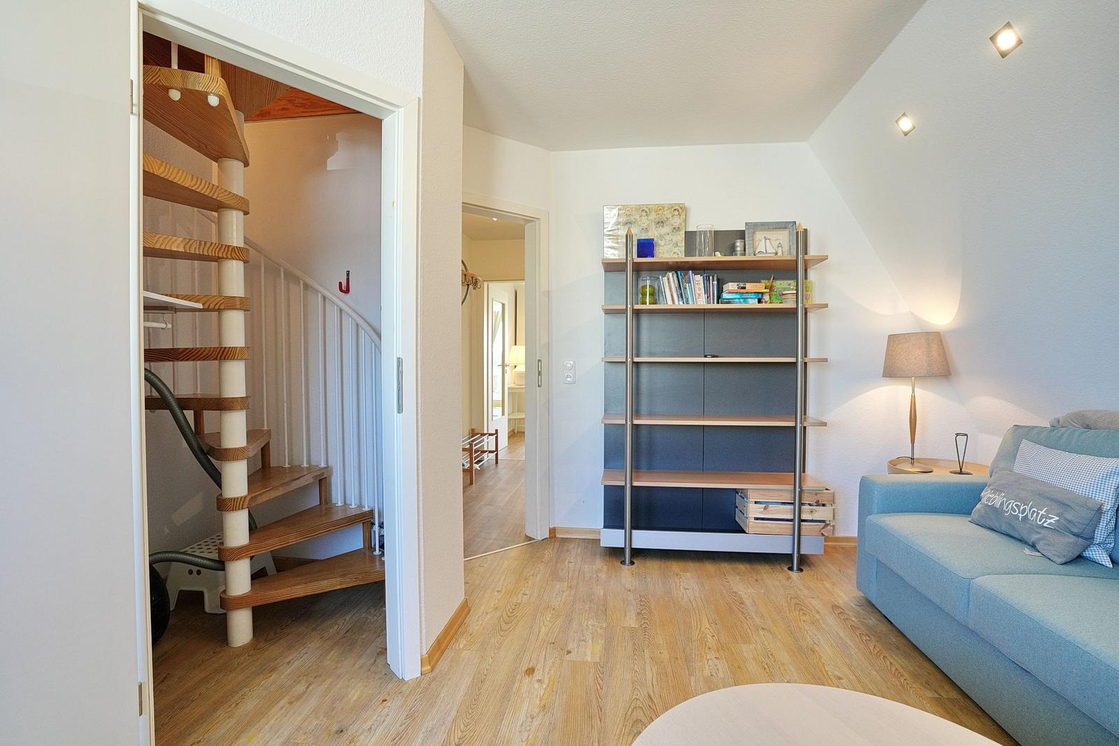 Wohnraum mit Sofa, Bücherregal und spiralförmiger Treppe.