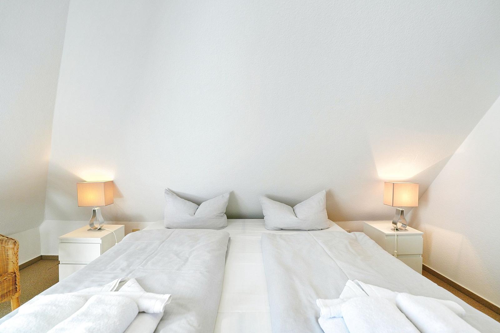 Schlafzimmer mit Doppelbett, zwei Nachttischen und Lampen an den Seiten.