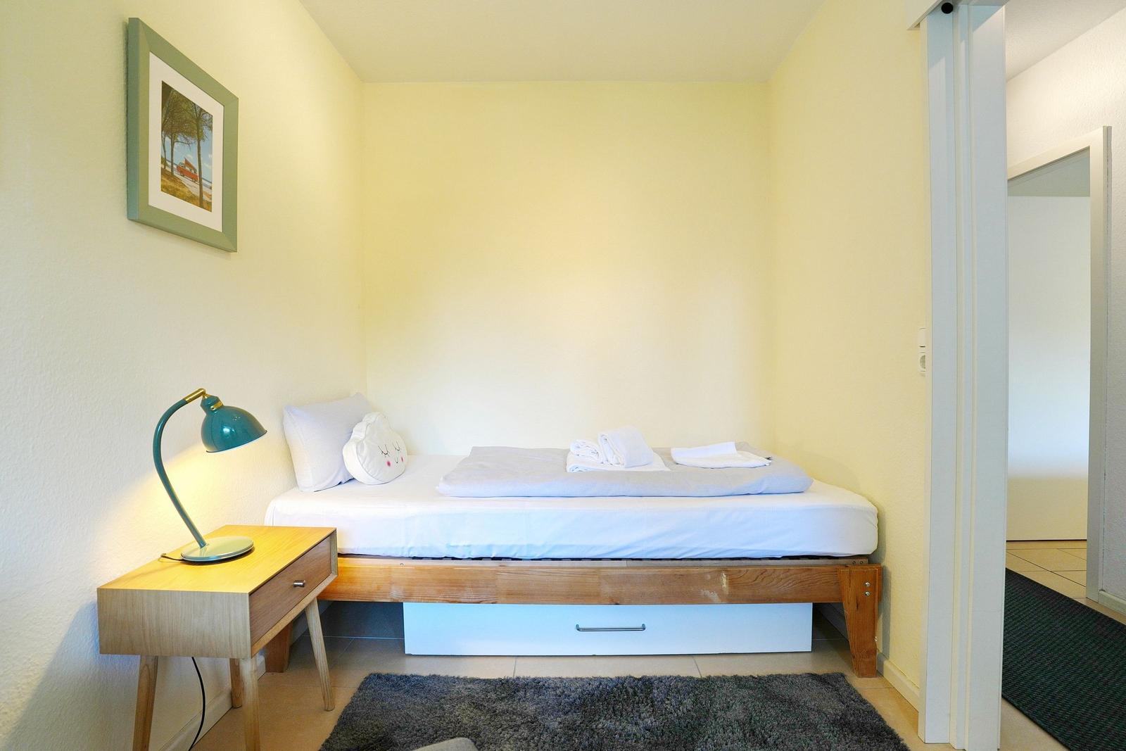 Ein Schlafzimmer mit einem Bett, Nachttisch und einer Wandlampe.