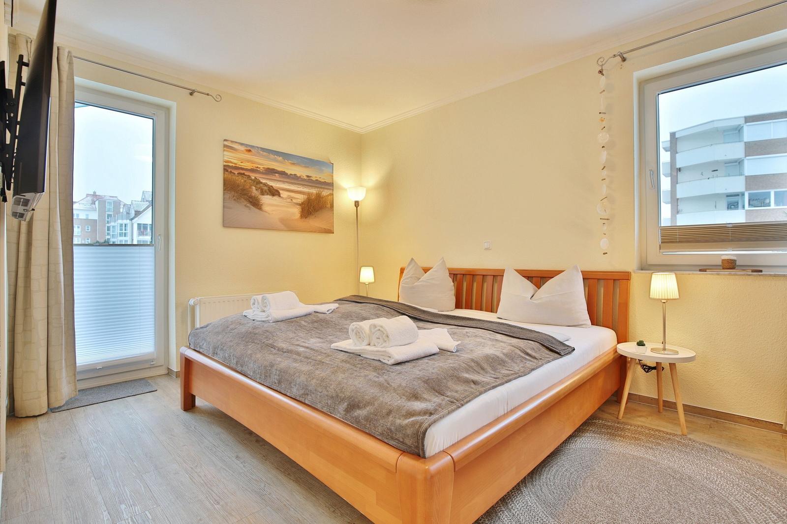 Bedroom with bed, windows, and wall art.