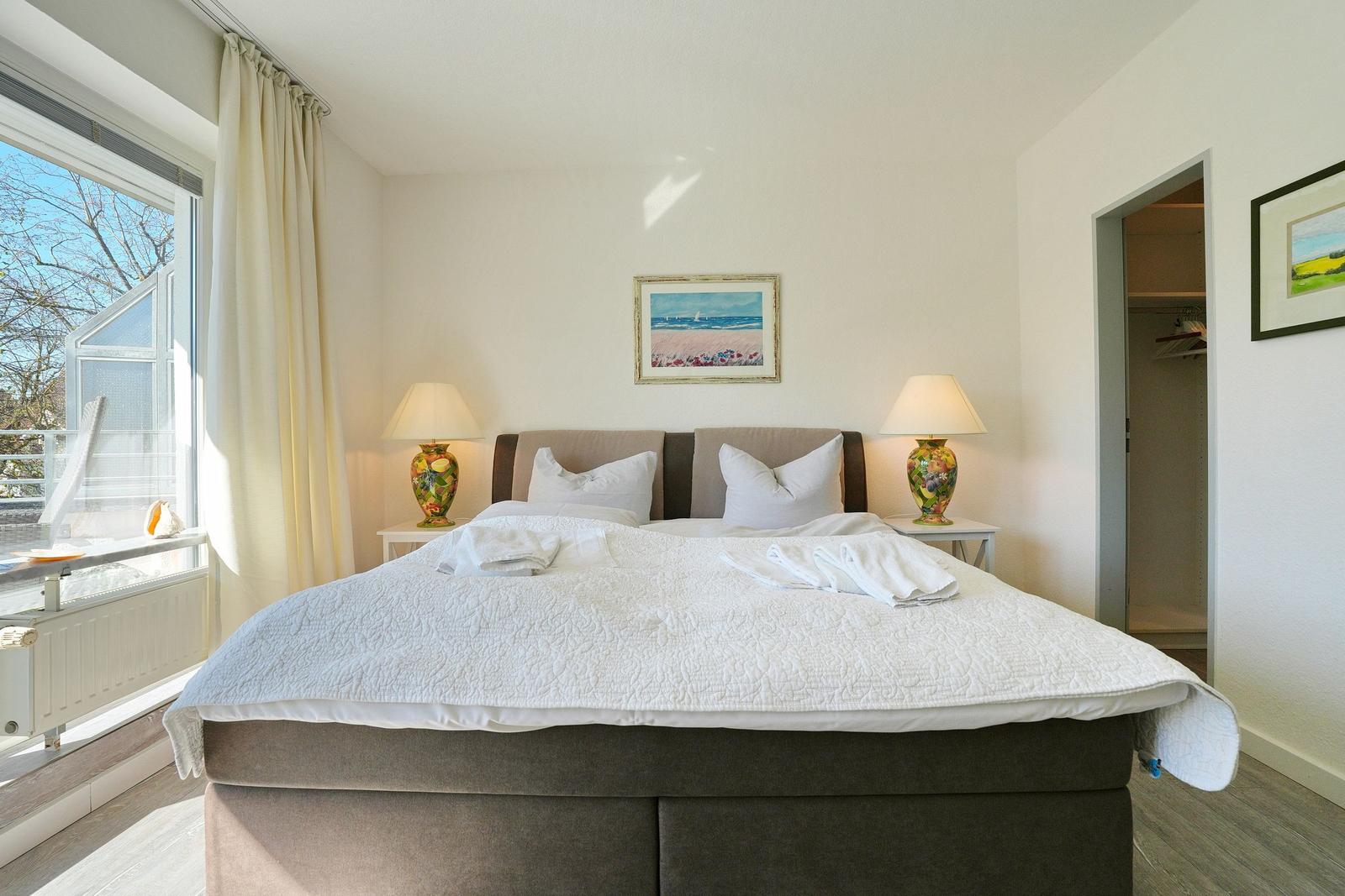 Schlafzimmer mit Doppelbett, zwei Nachttischen und Fenster mit Blick.