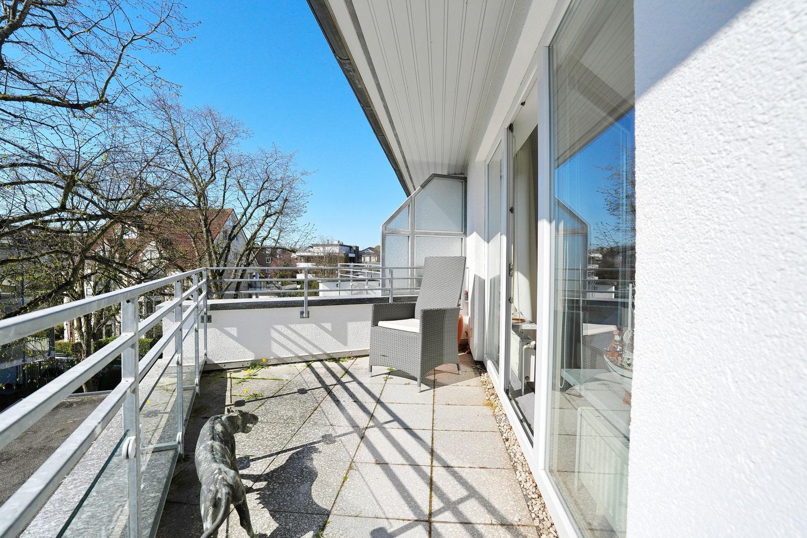 Terrasse mit Sitzgelegenheit und Blick auf Bäume und Nachbarhäuser.