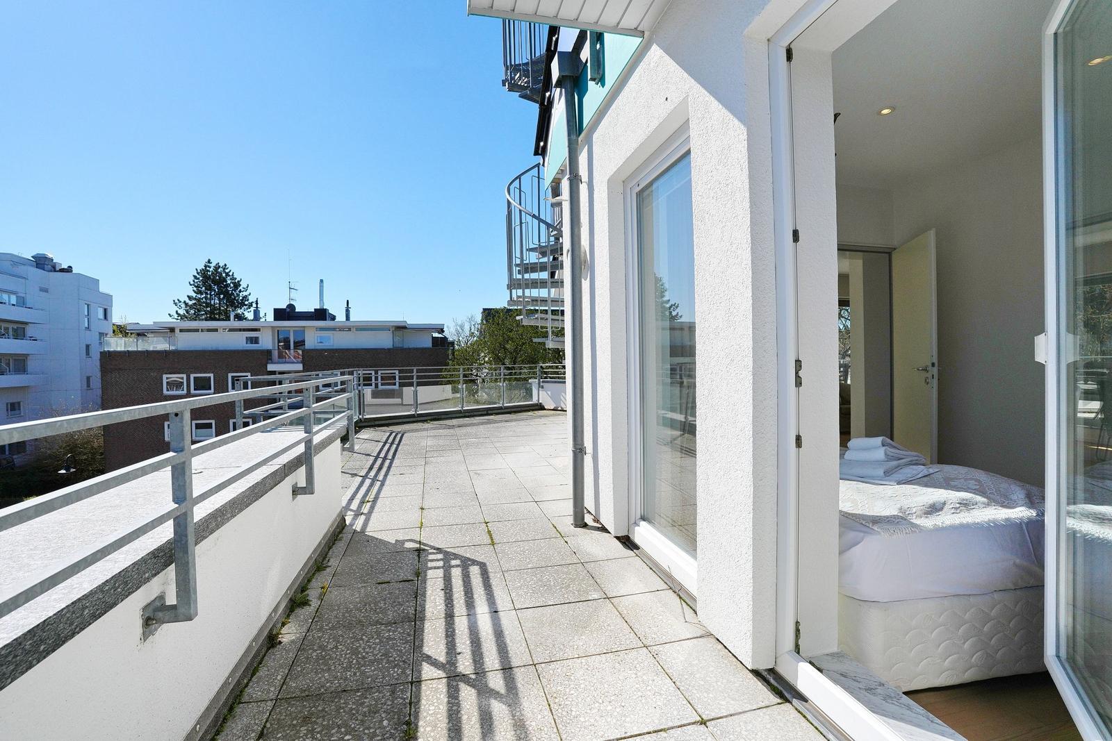 Terrasse mit Blick auf Gebäude und einen weißen Balkonbereich mit Bett.