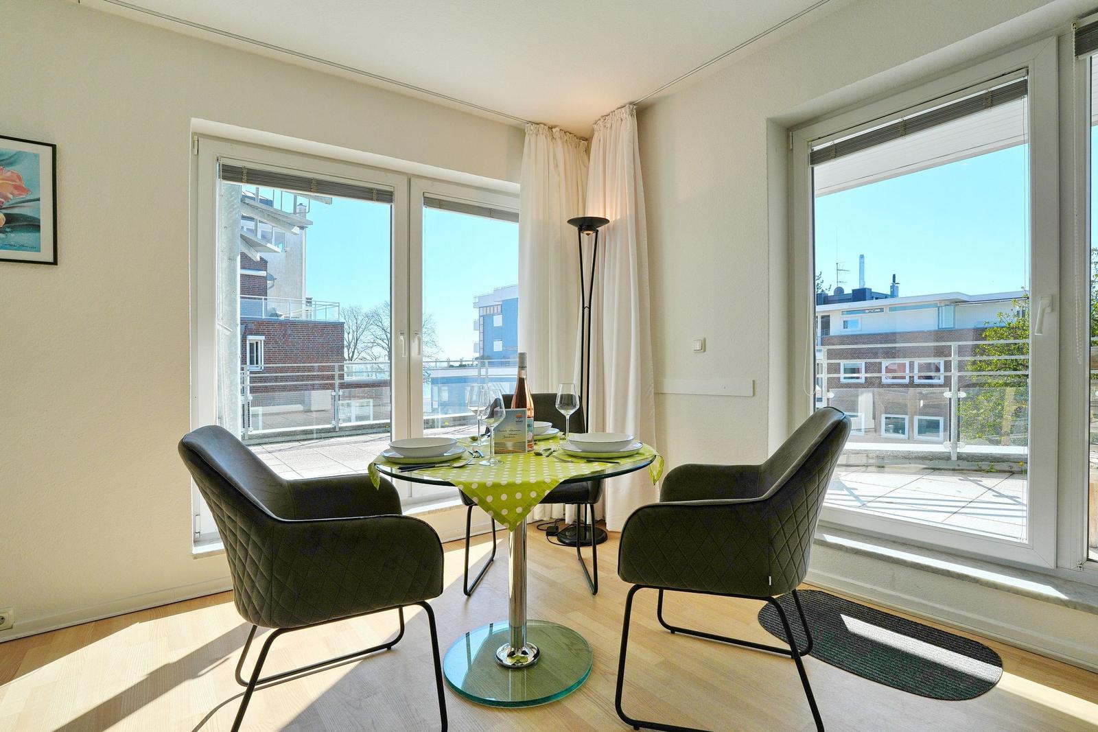 Essbereich mit Tisch, Stühlen und Blick auf Balkon.