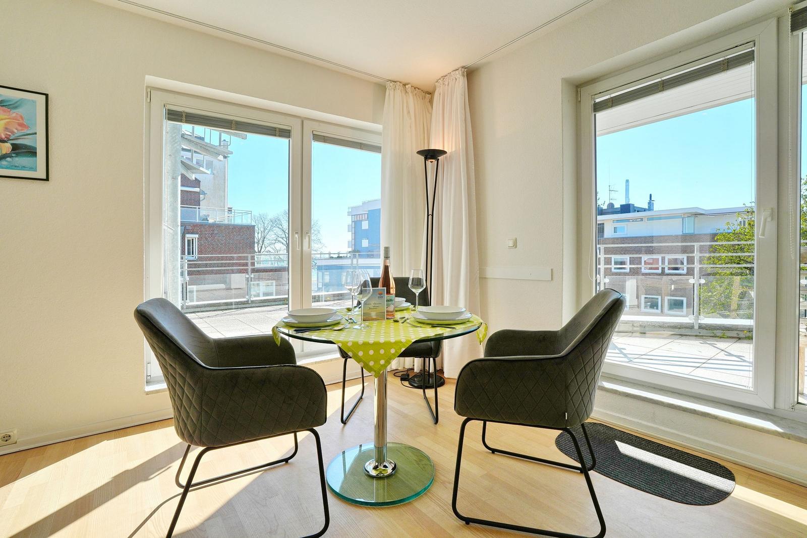 Essbereich mit Tisch, Stühlen und Blick auf Balkon.