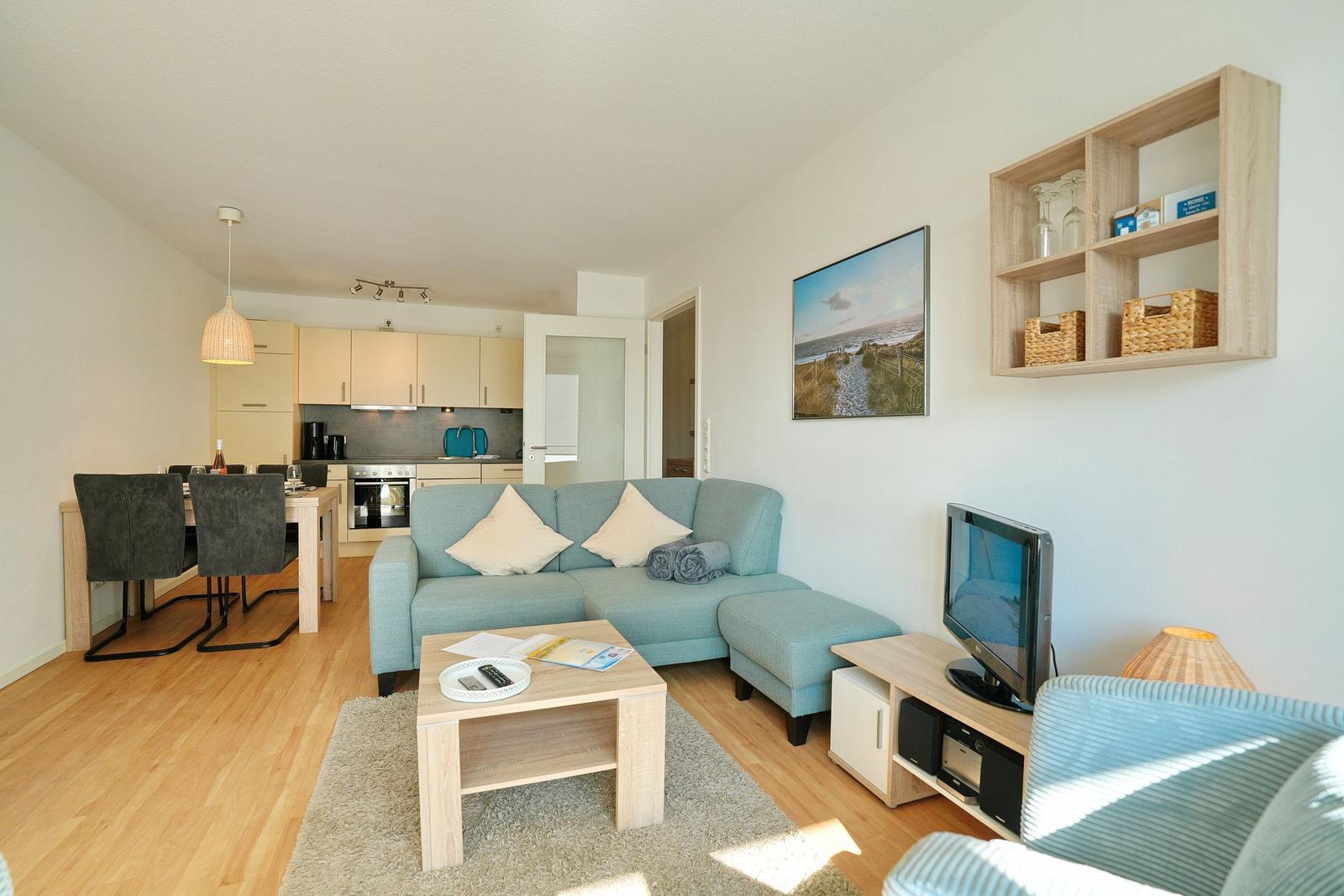 Wohnung mit Wohnzimmer, Küche und Essbereich. Sofa, Couchtisch und Fernseher sichtbar.