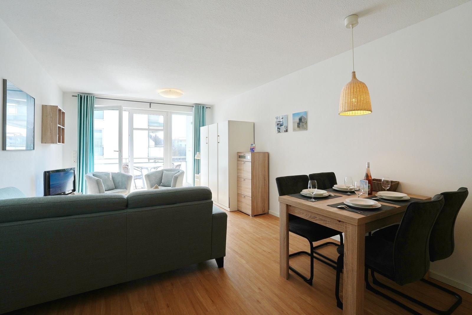 Wohn- und Essbereich mit Sofa, Esstisch und Blick auf Balkon.