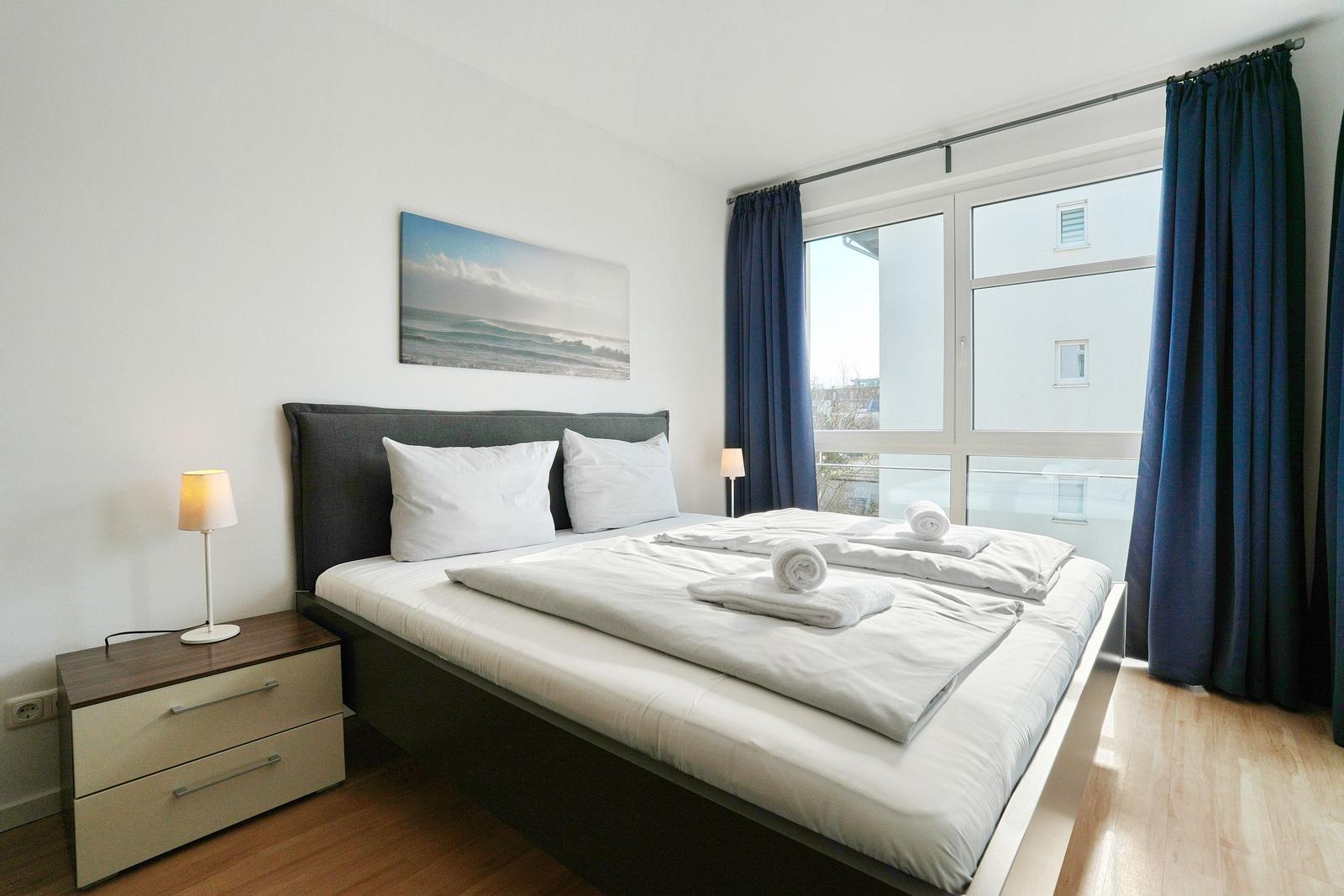 Schlafzimmer mit Bett, Nachttisch und Fenster mit Blick.