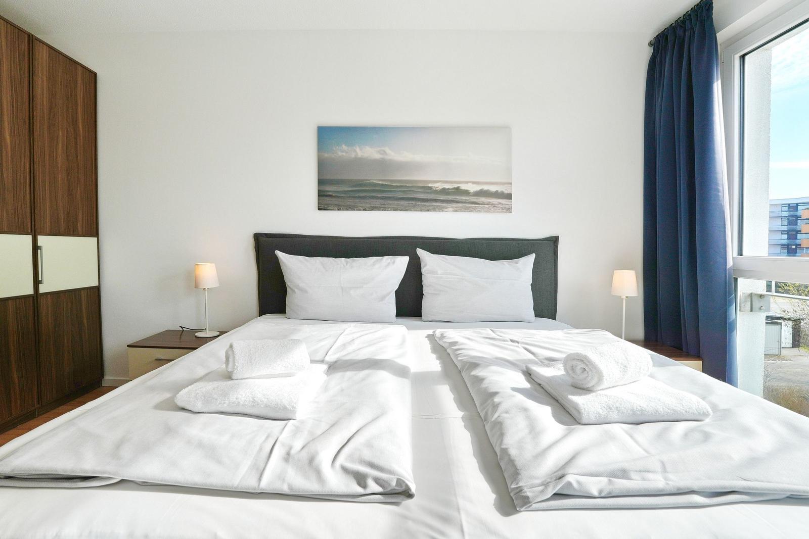Schlafzimmer mit Doppelbett, Wandbild und Fenster mit Blick.