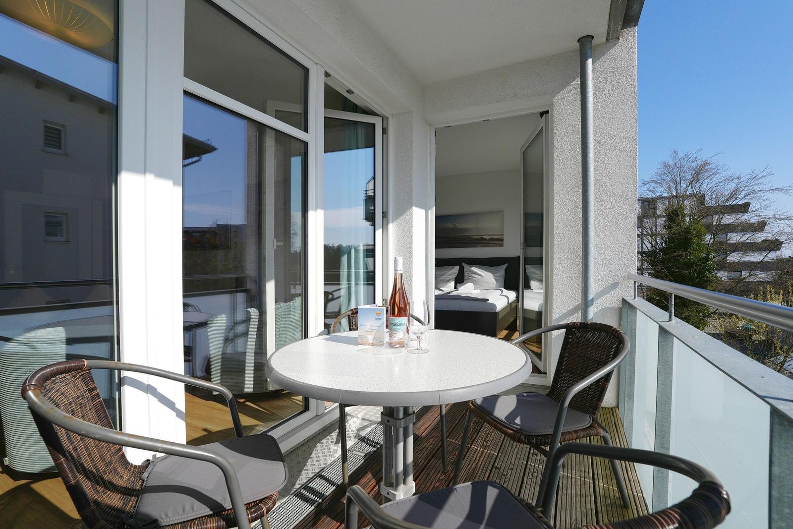 Terrasse mit Tisch und Stühlen. Im Hintergrund ist ein Schlafzimmer sichtbar.