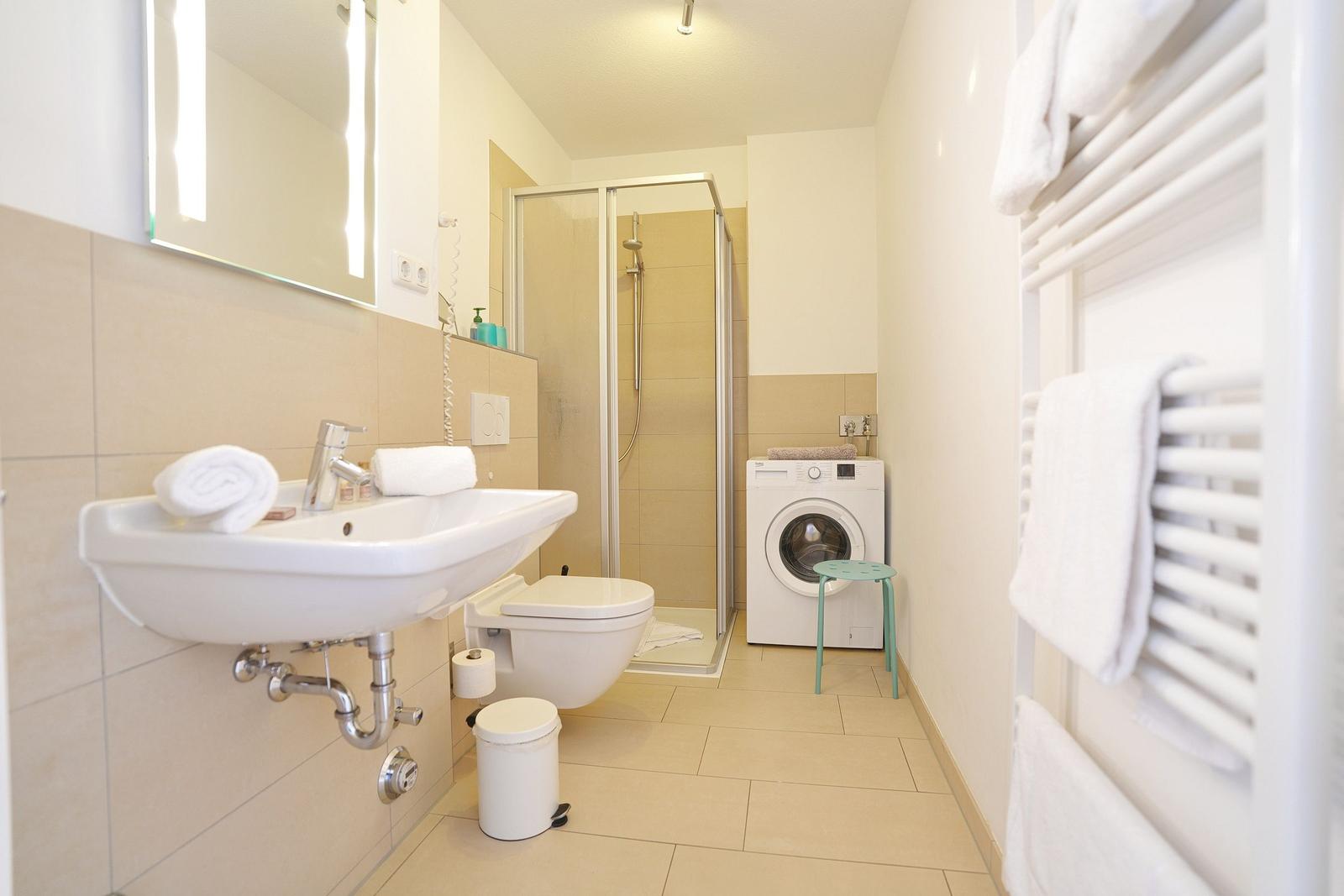 Badezimmer mit Dusche, Waschmaschine und Handtuchheizung.