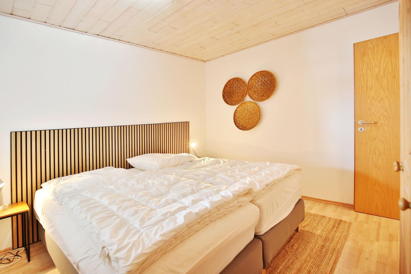 Schlafzimmer mit Bett, Holzdecke und Wanddekoration