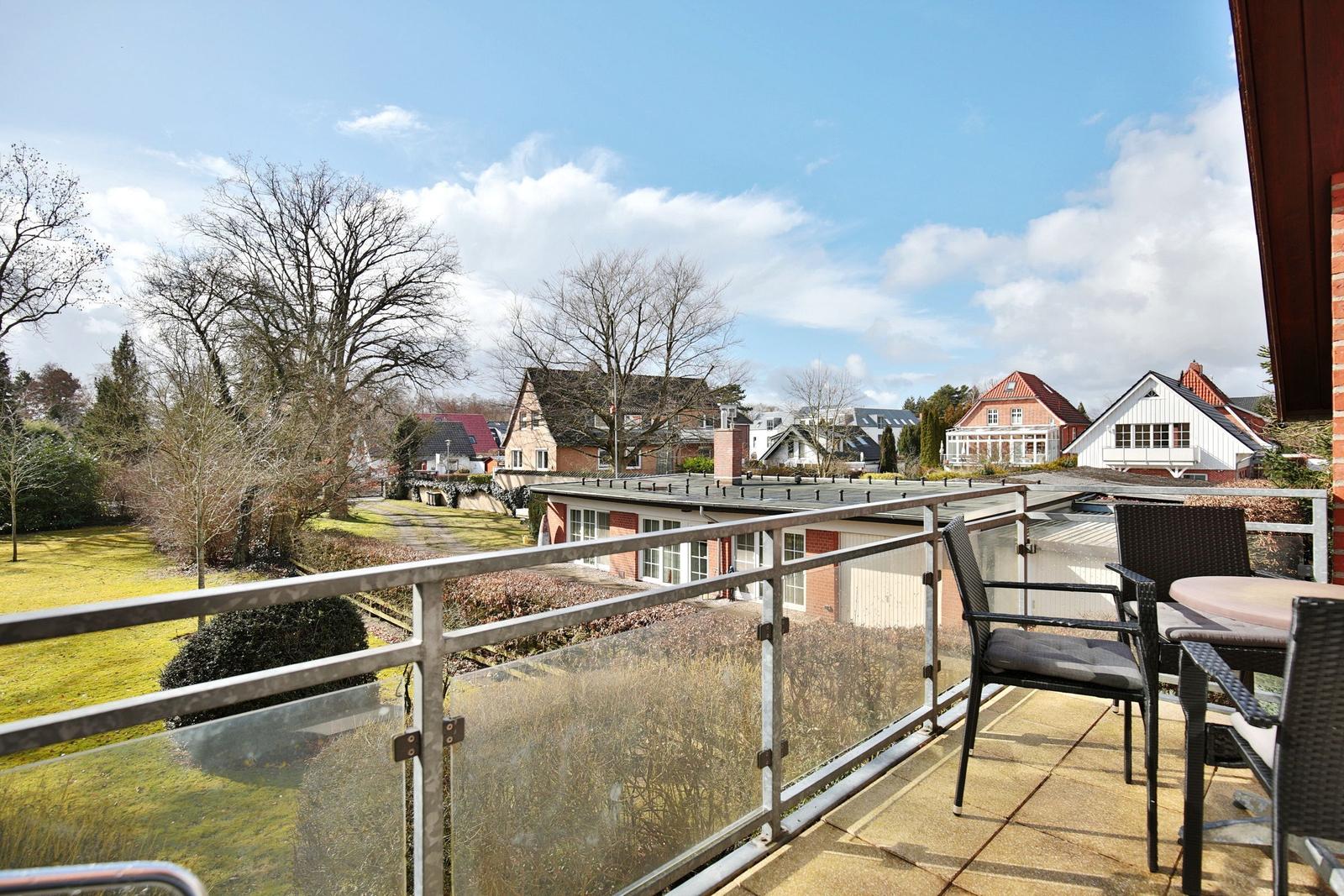 Terrasse mit Sitzgruppe und Blick auf Wohnhäuser und Grünflächen.