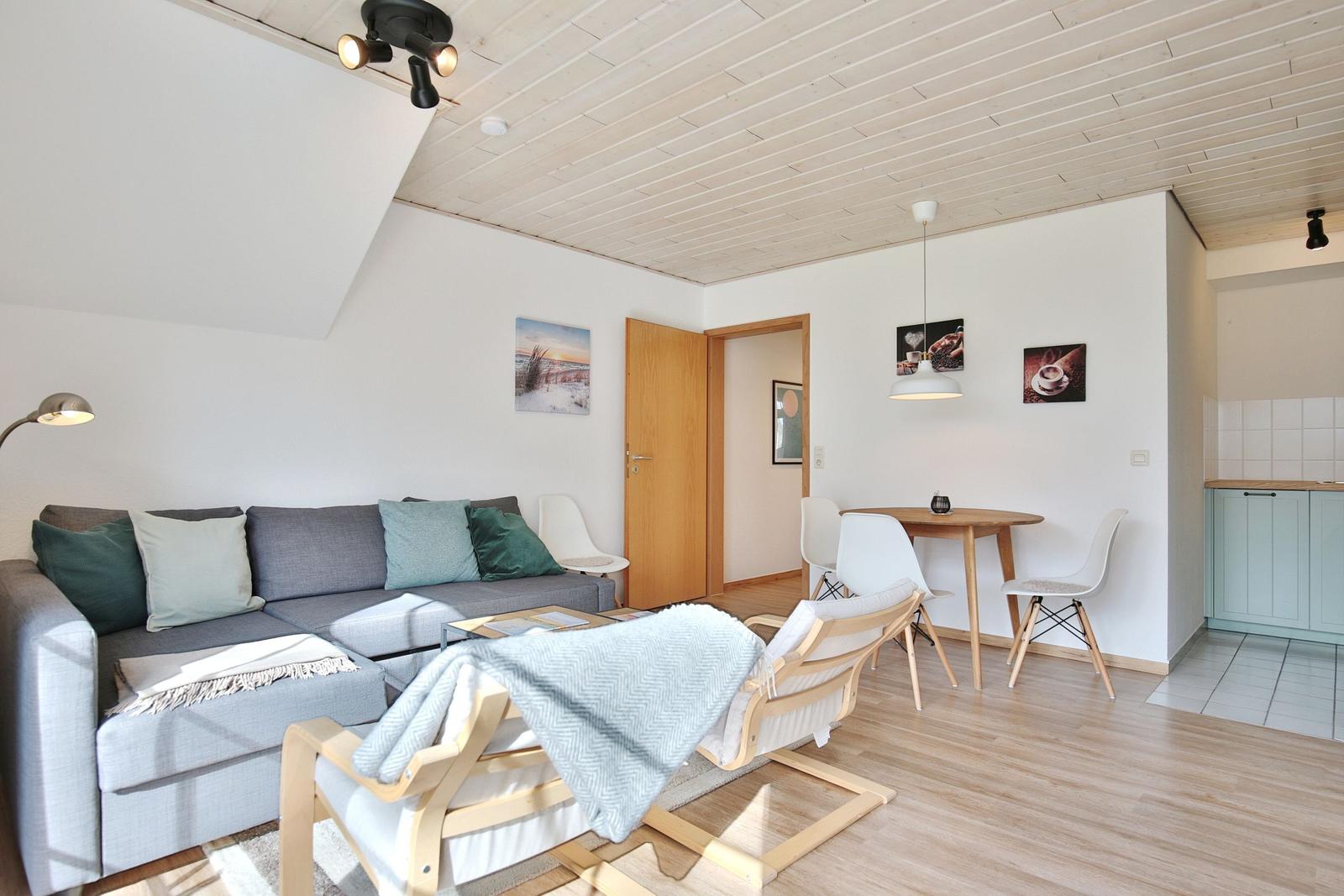 Wohnbereich mit Sofa, Essplatz und Küchenbereich. Holzdecke und -boden.