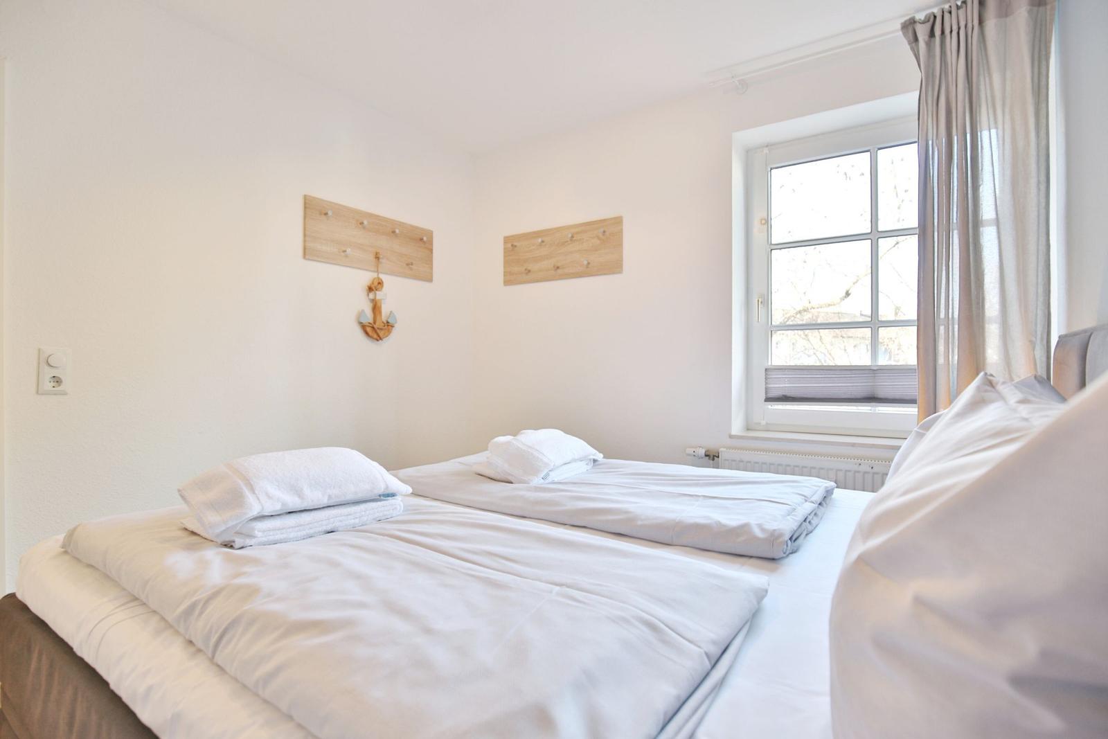 Zimmer mit Doppelbett, Fenster und Holzpaneelen an der Wand.