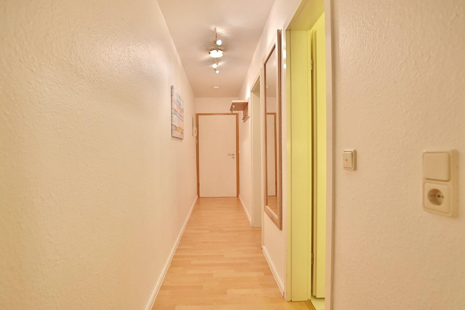 Flur mit Holzboden, Wandbild und Türen zu Räumen.