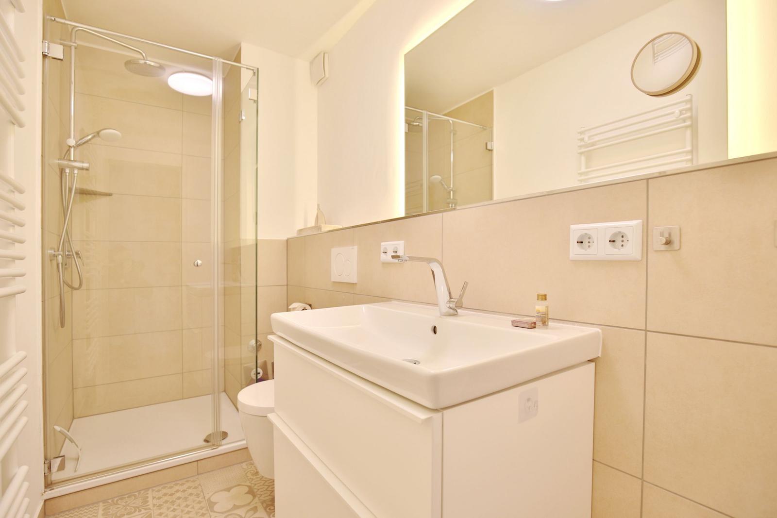 Badezimmer mit Dusche, Waschbecken und Spiegel