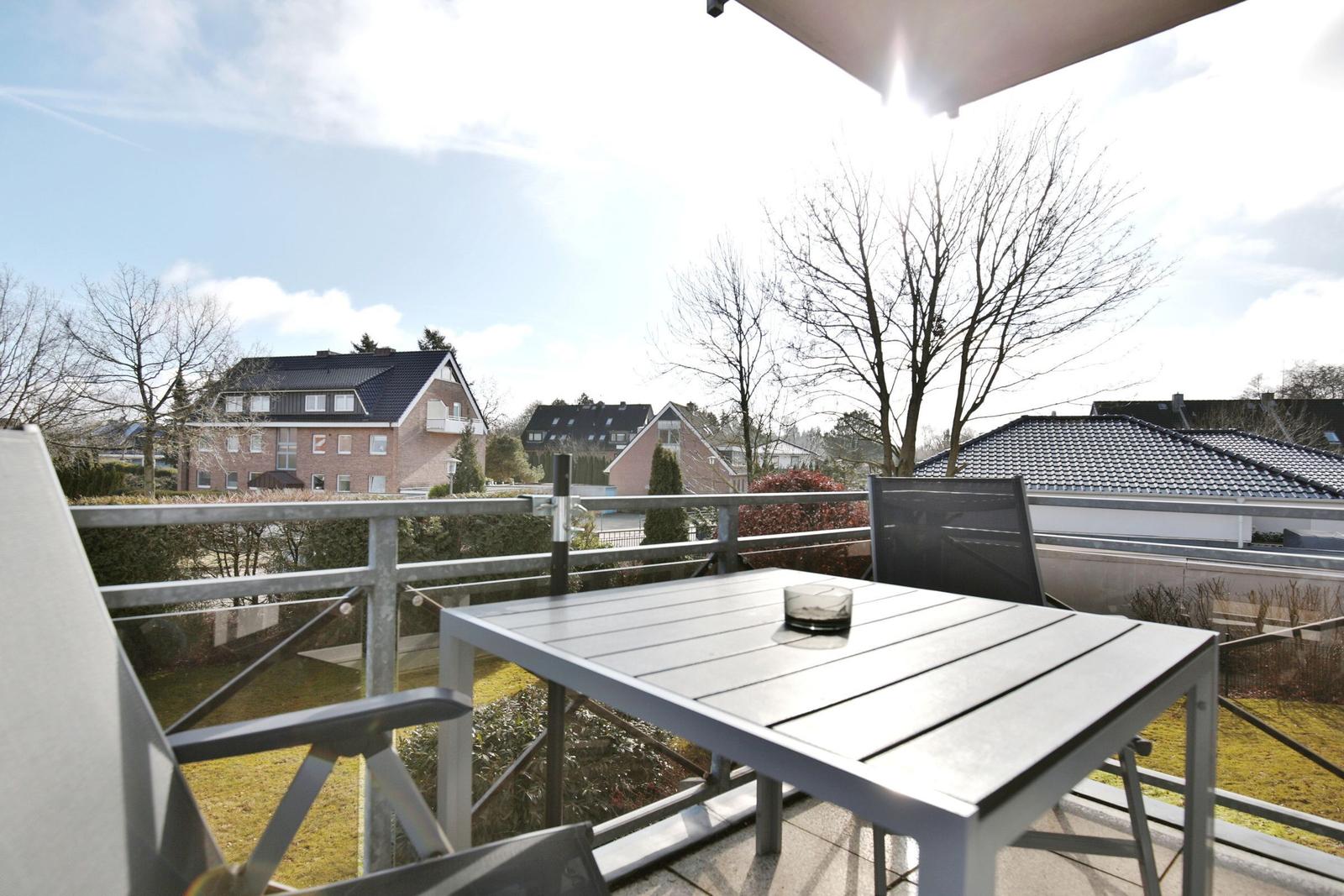 Terrasse mit Tisch und Stühlen. Blick auf Wohnhäuser und Bäume.