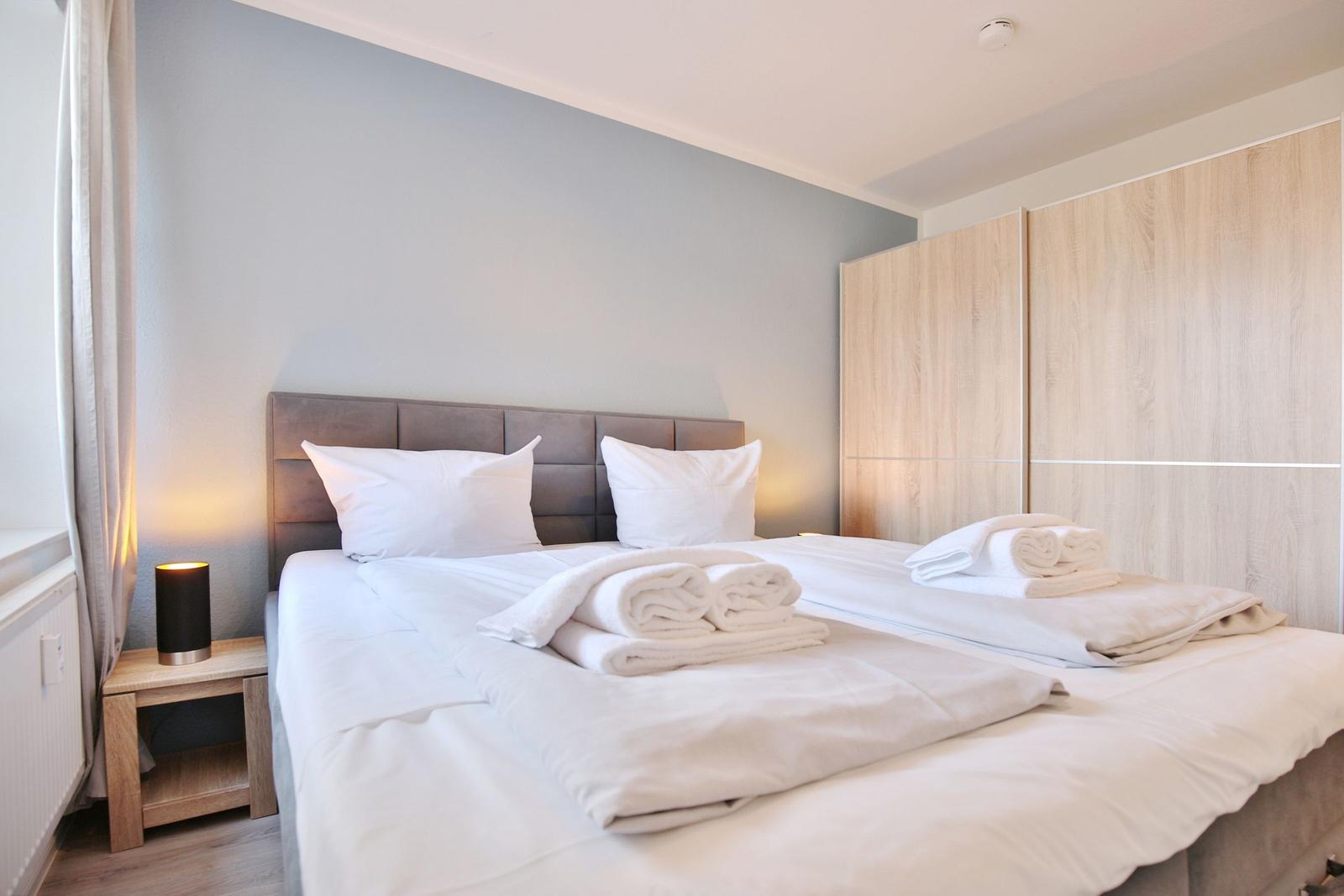 Ein Schlafzimmer mit Doppelbett, weißen Bettwäsche und Holzmöbeln.