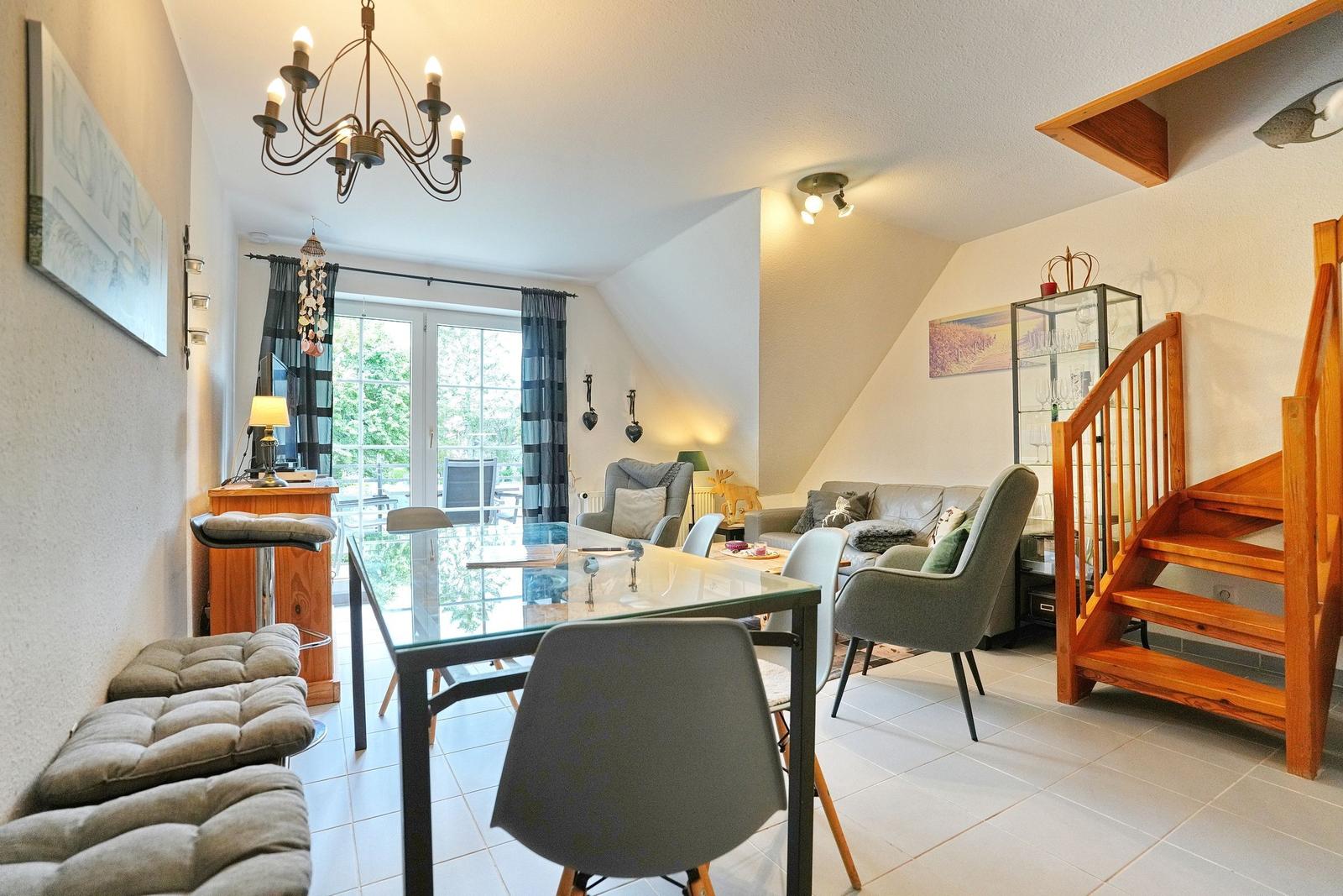 Erdgeschoss mit Essbereich, Wohnzimmer und Holztreppe.