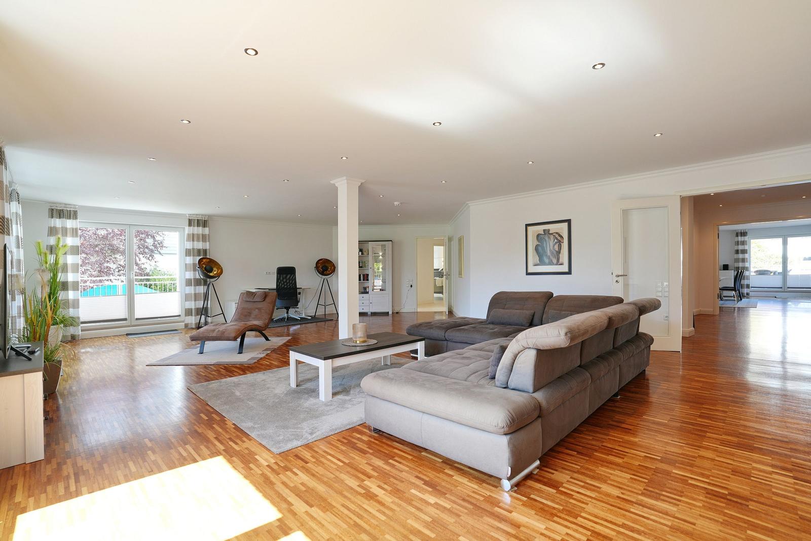 Wohnzimmer mit Sofa, Couchtisch und Holzboden. Durchgang zu weiteren Räumen.