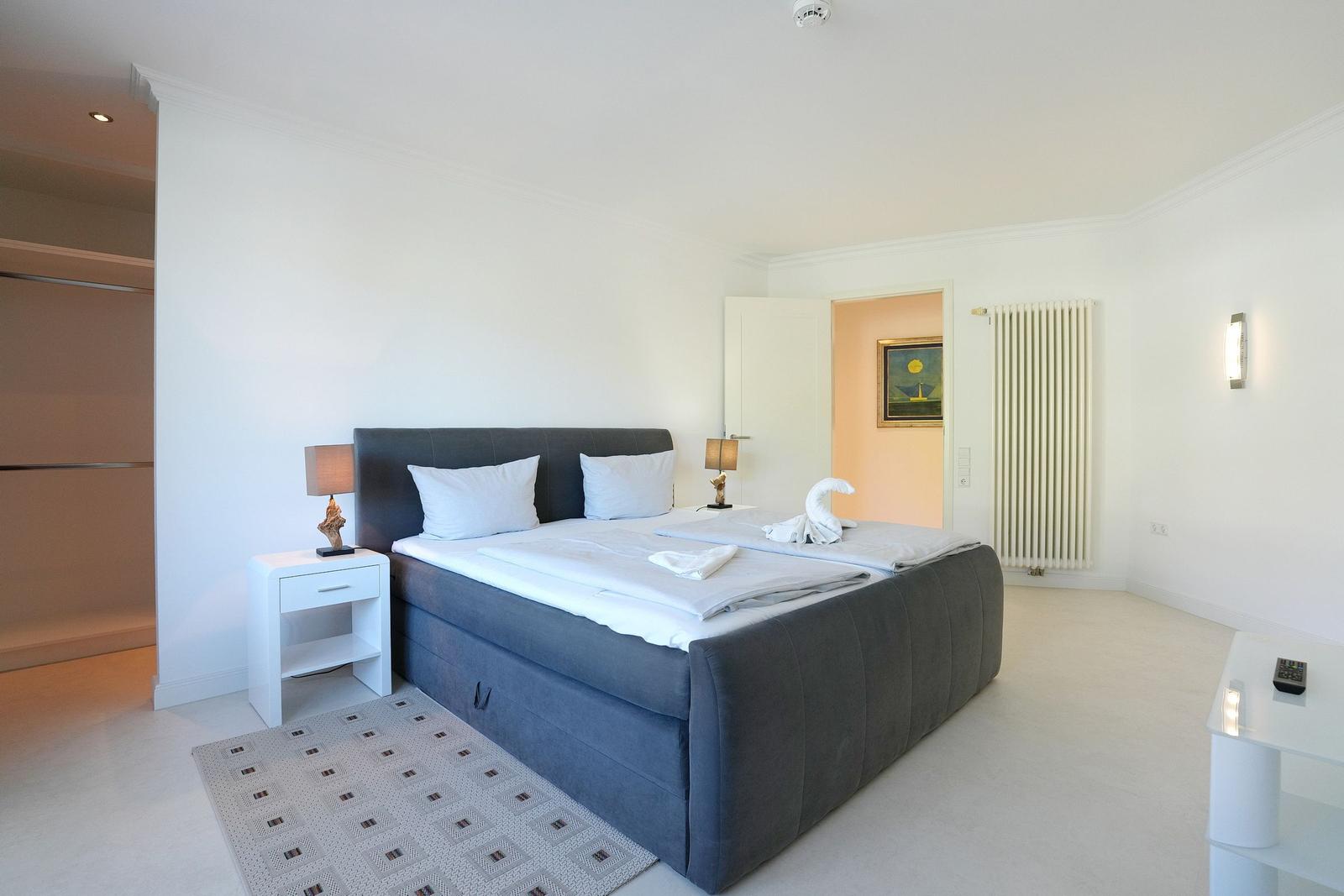 Schlafzimmer mit Doppelbett, Nachttisch und Kleiderschrank.