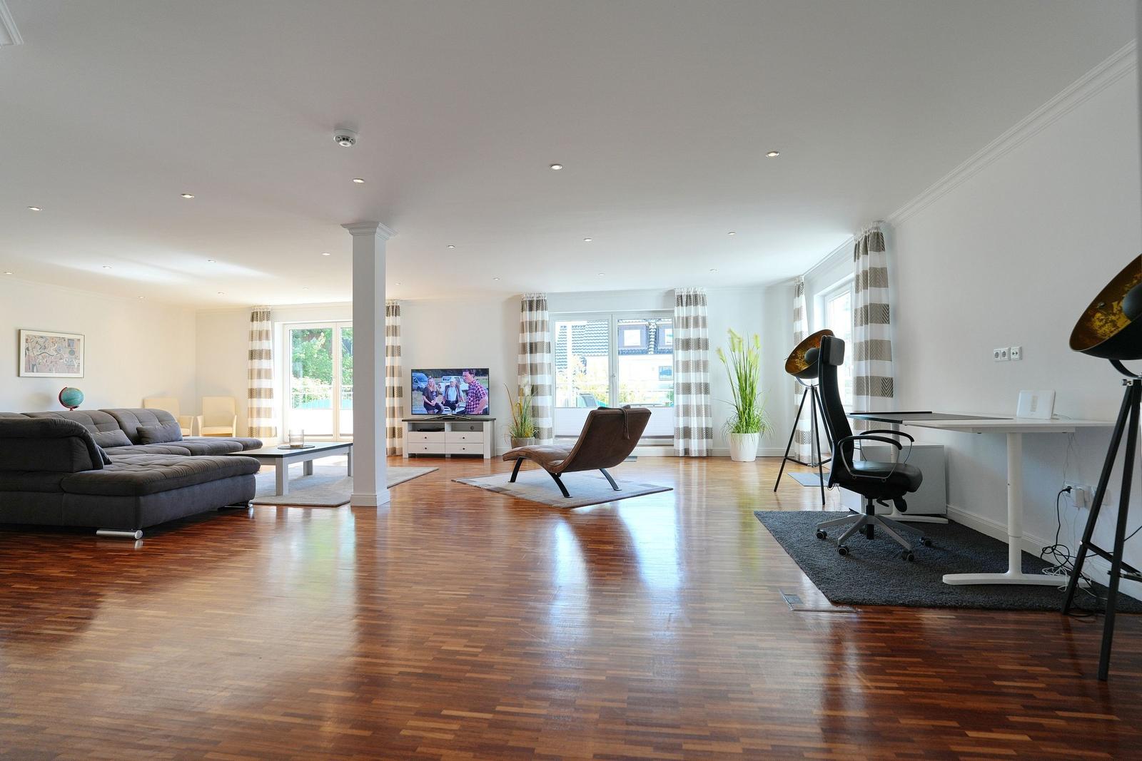 Wohnraum mit Holzboden, Sofa, Fernseher und Schreibtisch mit Stuhl.