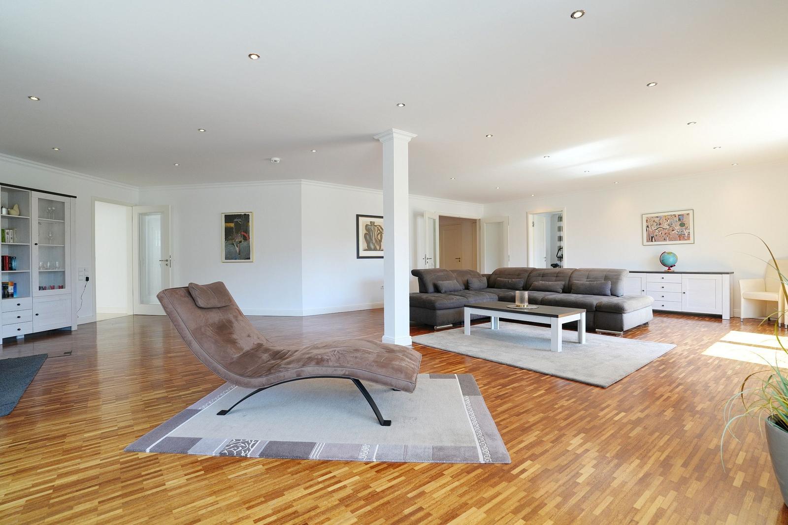 Wohnzimmer mit braunem Liegesofa, Holzboden und weißen Wänden.