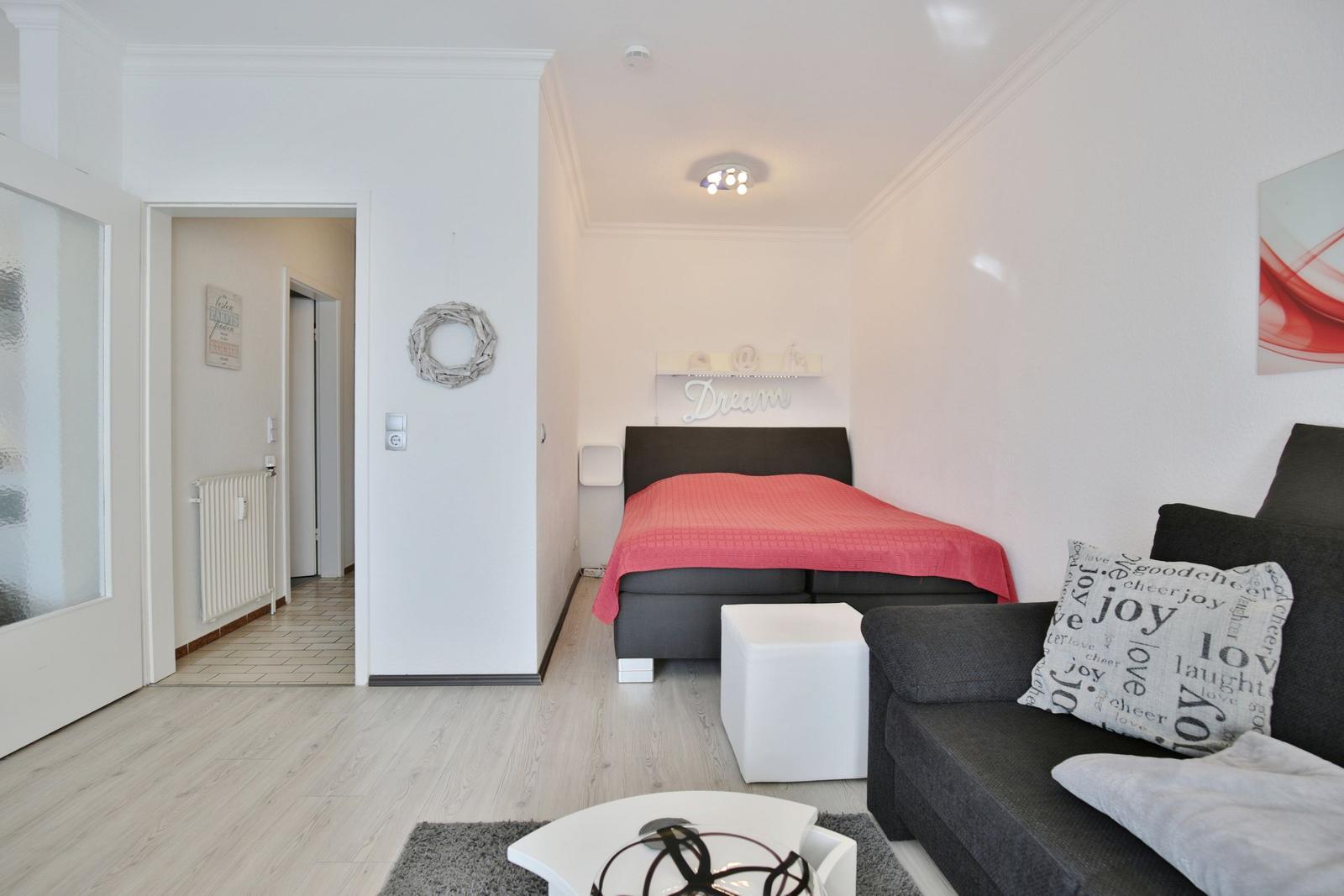 Schlafzimmer mit Bett, Sofa und Wanddekoration.
