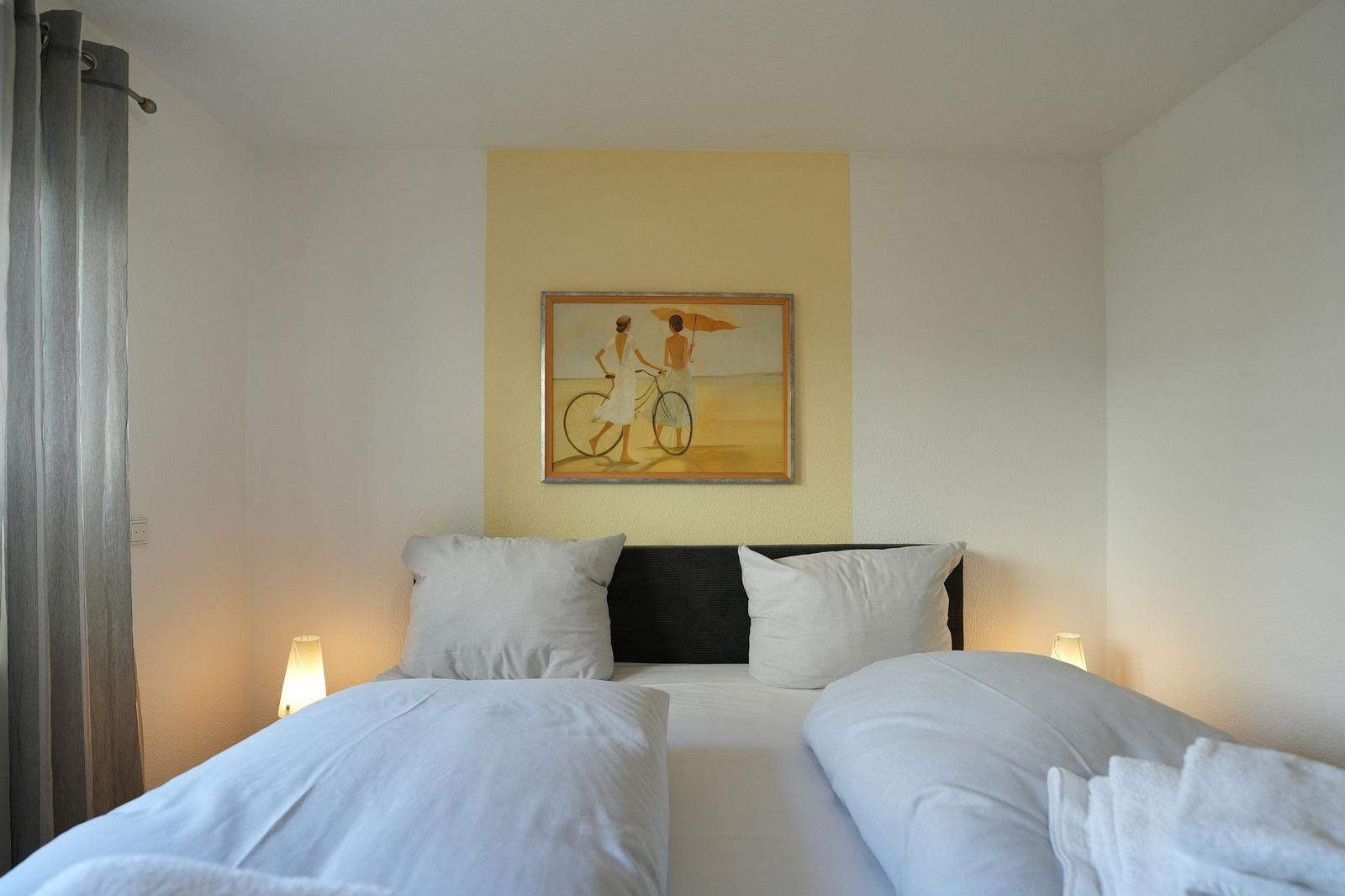 Schlafzimmer mit Doppelbett, Wandbild und Beleuchtung an den Bettkanten.