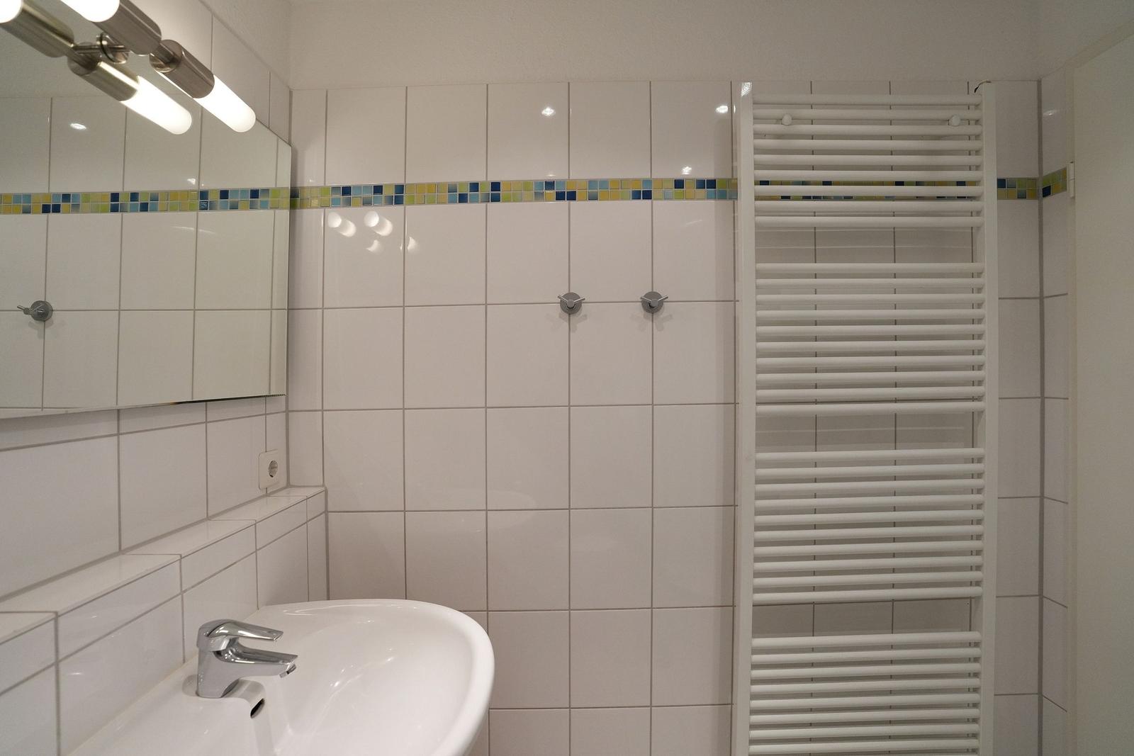 Badezimmer mit Waschbecken, Spiegel und Heizkörper