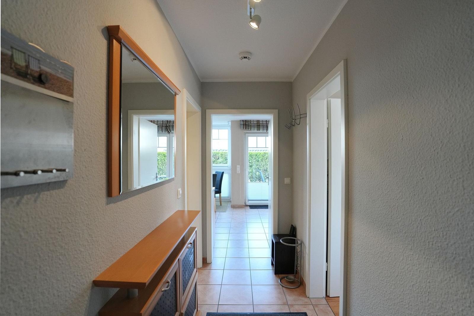 Flur mit Spiegel, Schrank und Blick in Wohnbereich mit Terrasse.