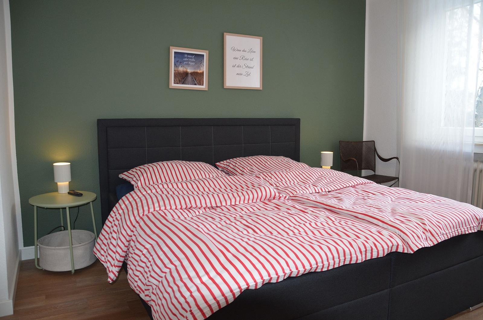 Schlafzimmer mit Bett, Nachttisch und Bildern an der Wand.
