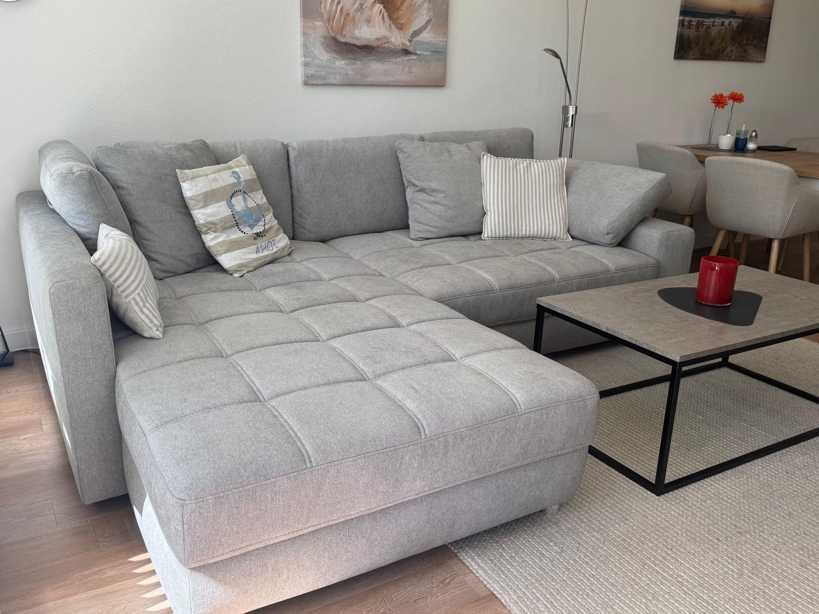 Großer grauer Ecksofa mit Kissen und Couchtisch im Wohnbereich.